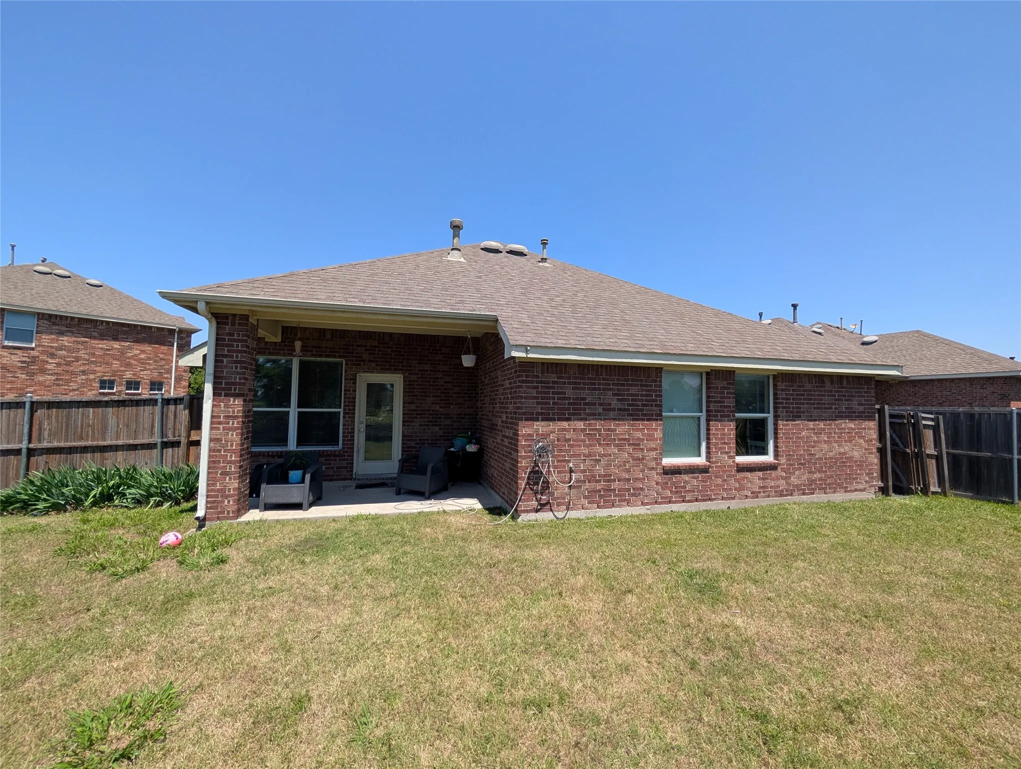 Brick exterior with a covered patio and a shingle roof