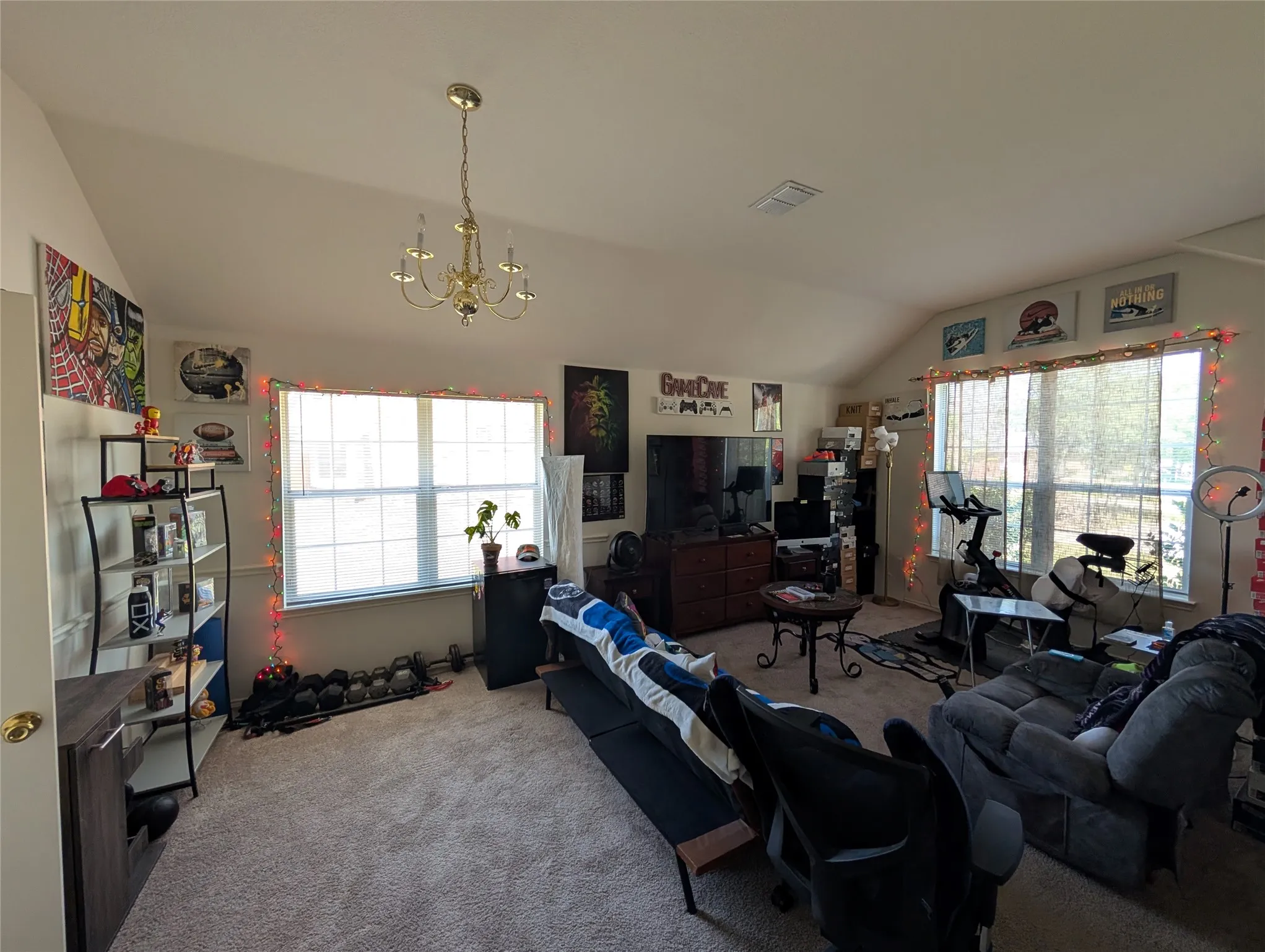 Carpeted room with vaulted ceilings and a brass chandelier