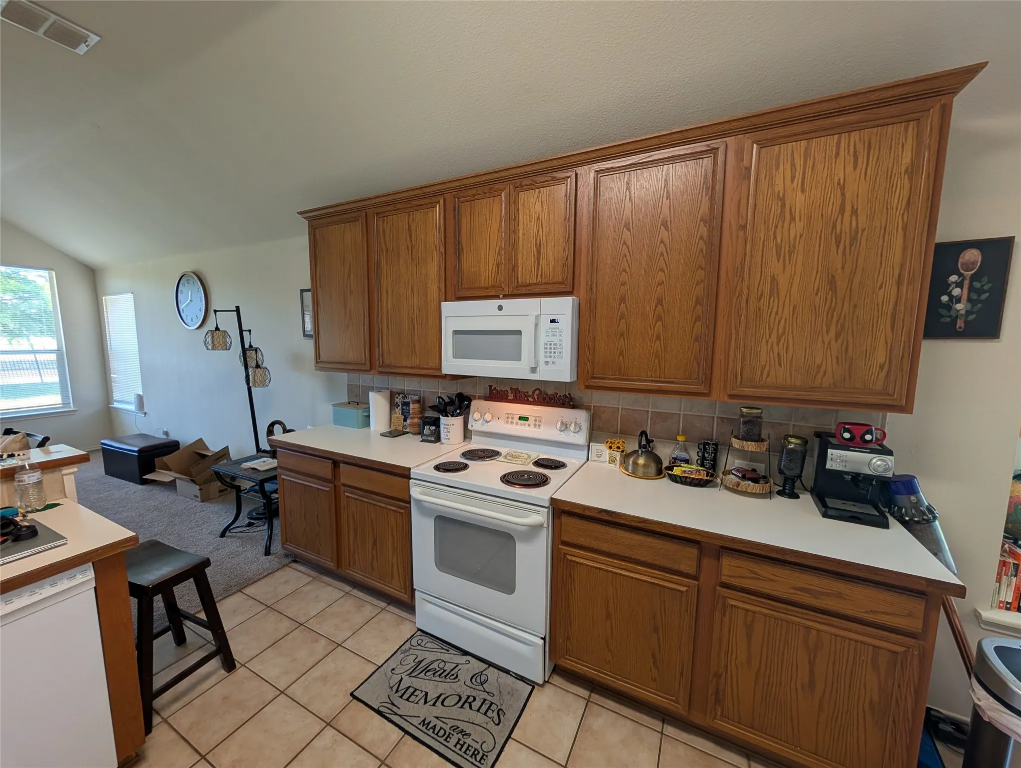 Kitchen featuring wood-finish cabinetry with crown molding, white countertops, and a neutral tile backsplash