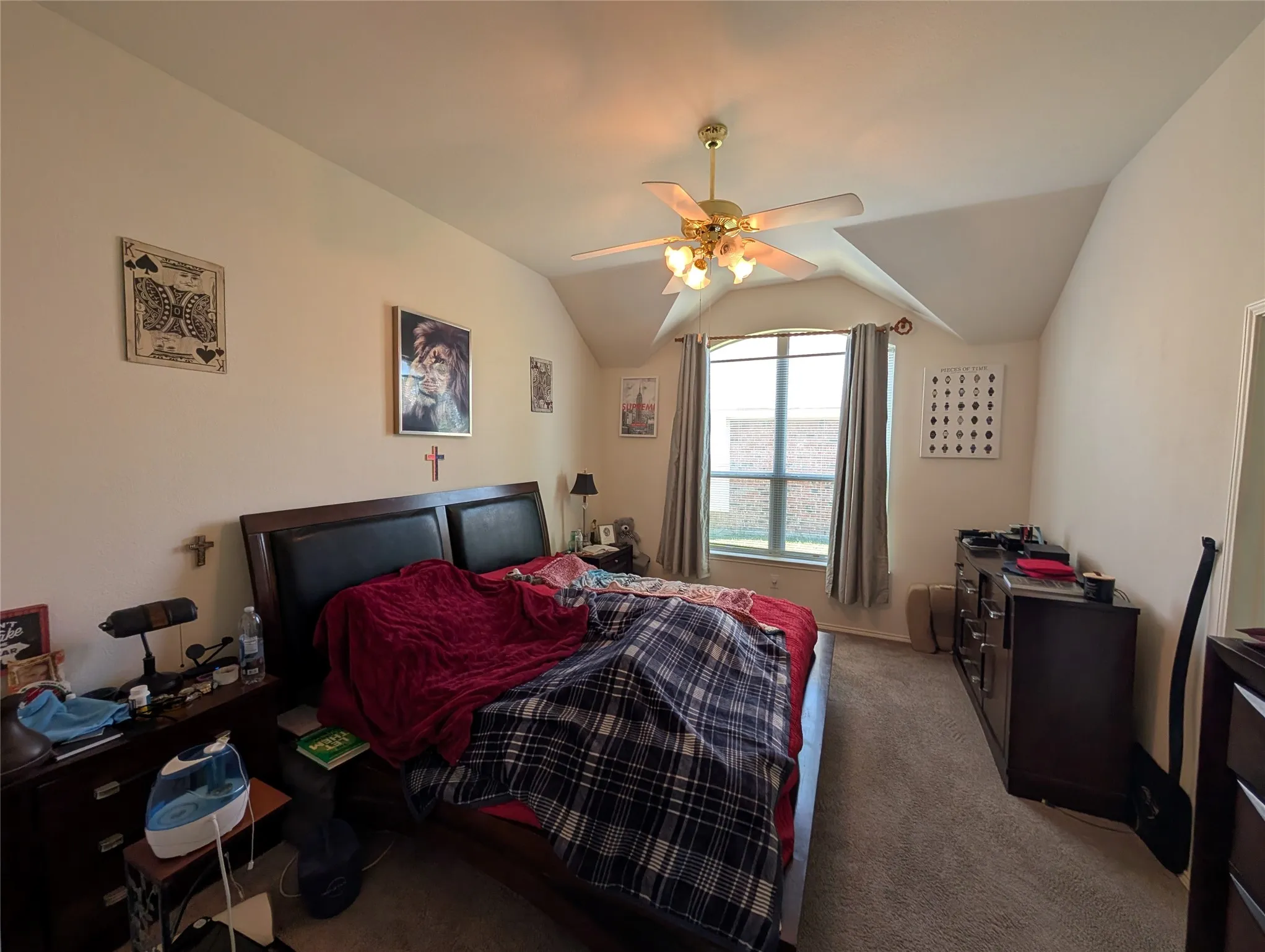 Vaulted ceiling bedroom featuring a ceiling fan with integrated lighting, carpet flooring, and a large window with blinds