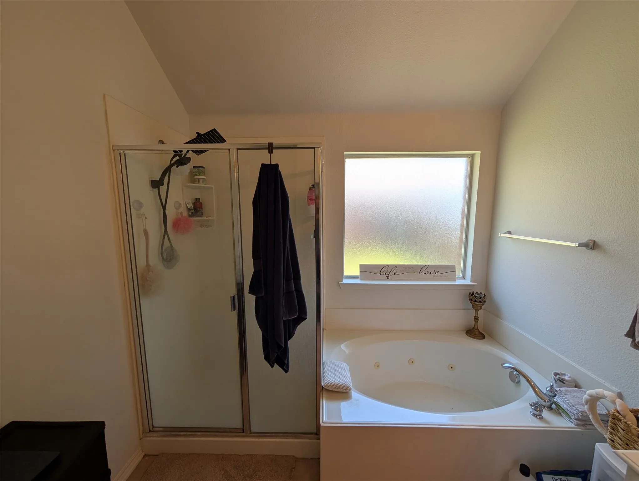Spacious bathroom featuring a built-in jetted tub, a frosted-glass window, and a separate glass-enclosed shower