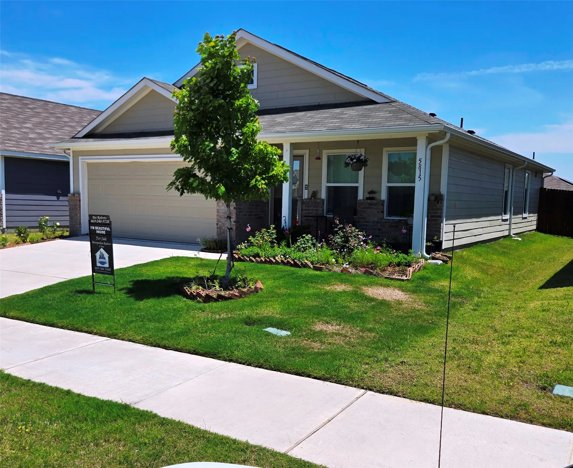 Craftsman single-story residence featuring light beige siding, a dark shingle roof, and an attached two-car garage