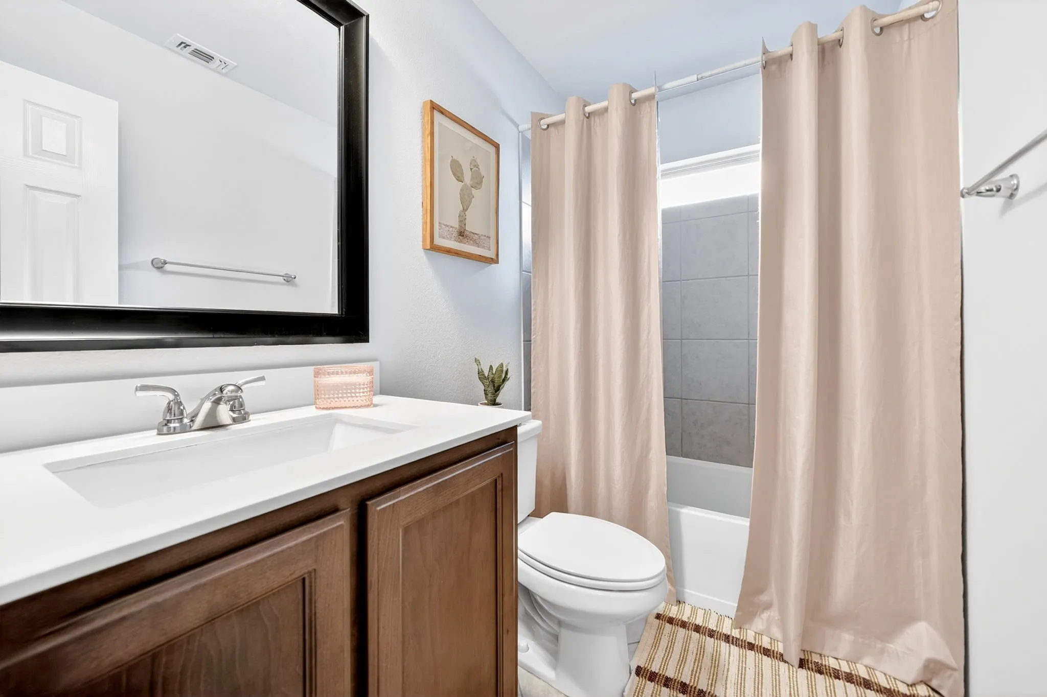 Bathroom featuring a single vanity with wood-finish cabinetry, a white integrated sink, and a framed mirror