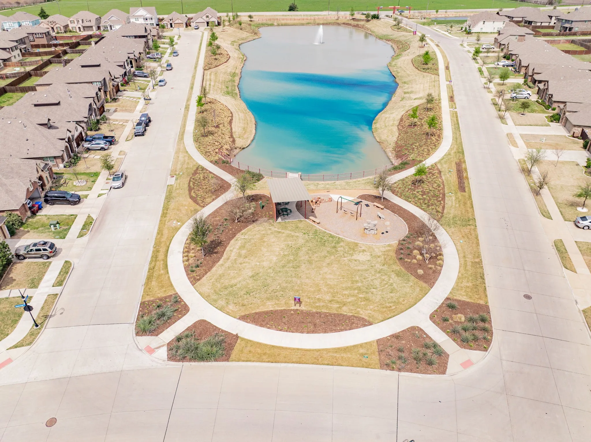Community park with a playground, covered seating area, and a central pond featuring a fountain