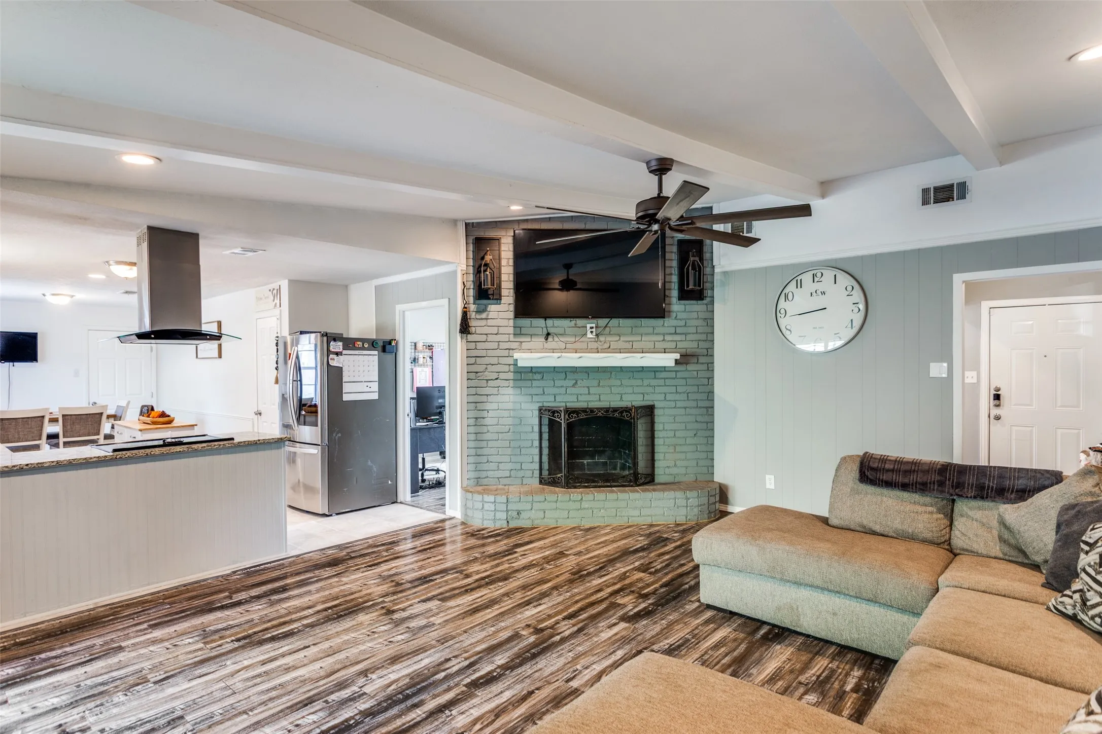 Open-concept living area featuring wood-finish flooring and exposed ceiling beams