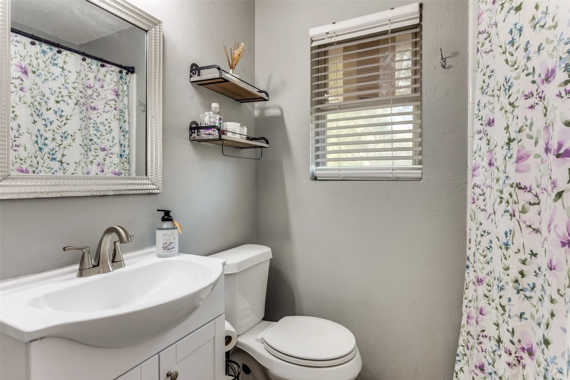 Bathroom featuring a single vanity with an integrated sink, brushed nickel faucet, and white cabinetry