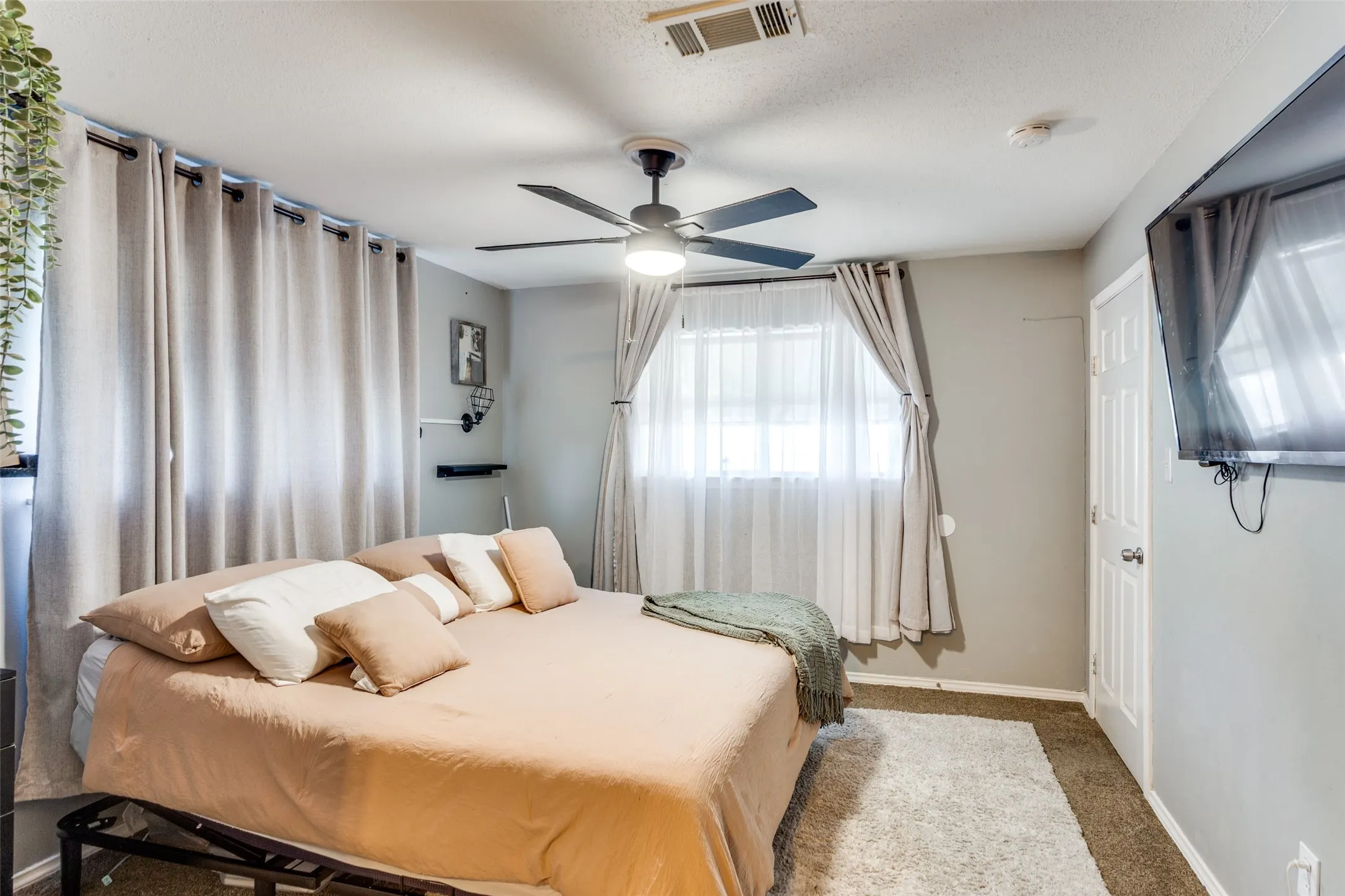 Bedroom featuring a ceiling fan with integrated lighting, wall-mounted shelving, and a paneled door