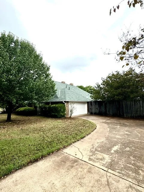 Back exterior with 2 car garage and privacy fence with a swimming pool.