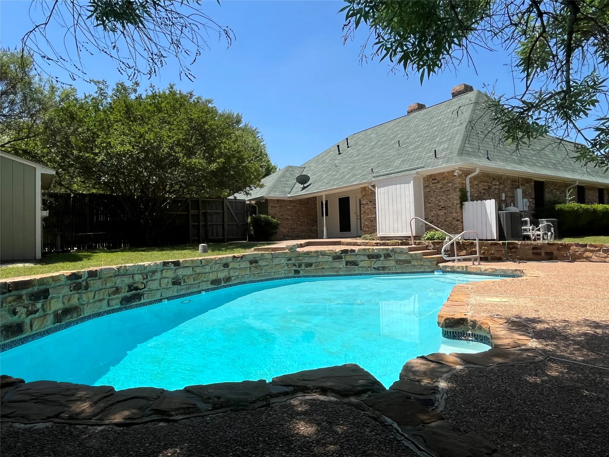 Inviting swimming pool with stone coping and retaining wall