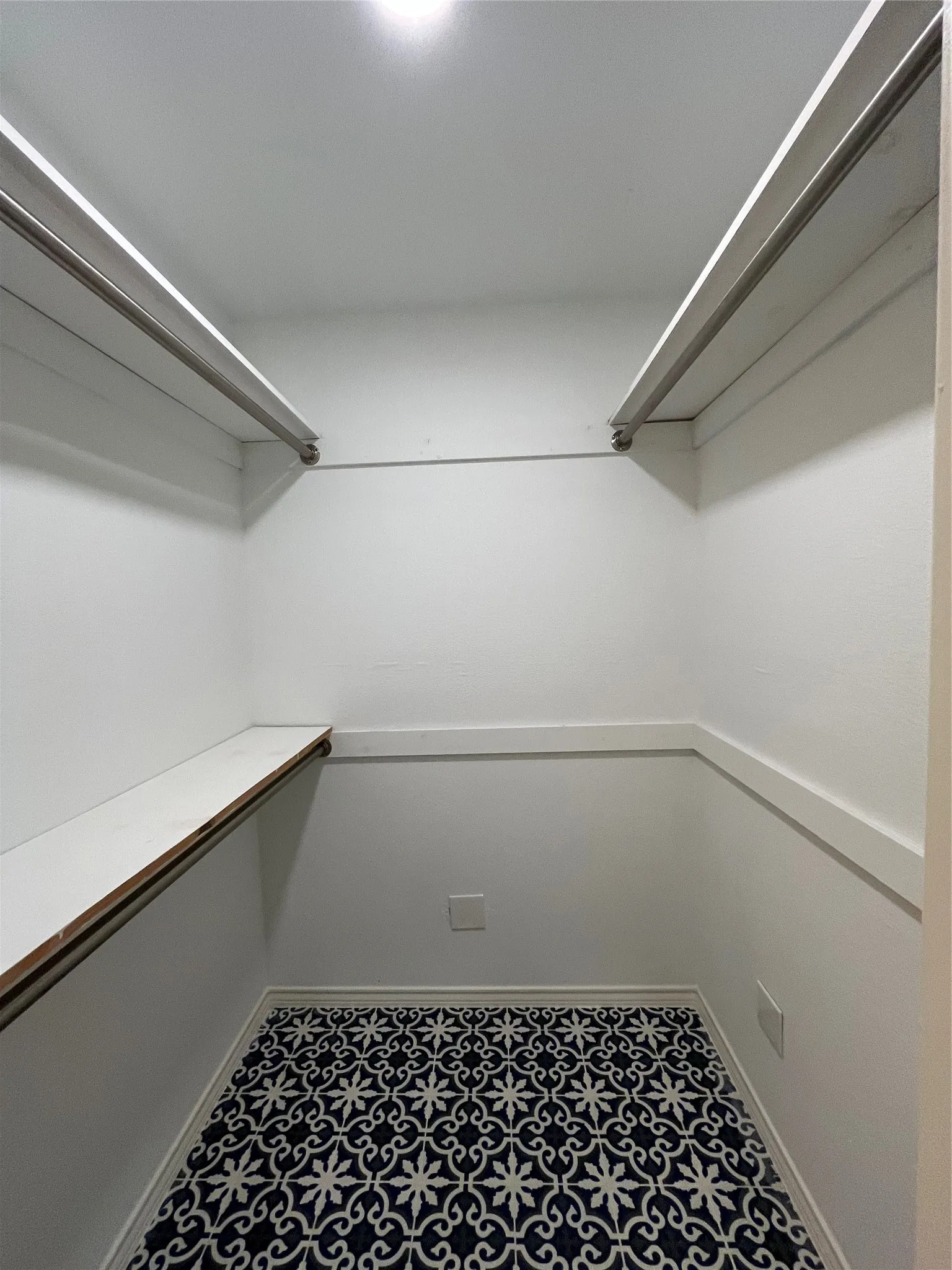 Walk-in closet featuring patterned floor tile and dual clothing rods