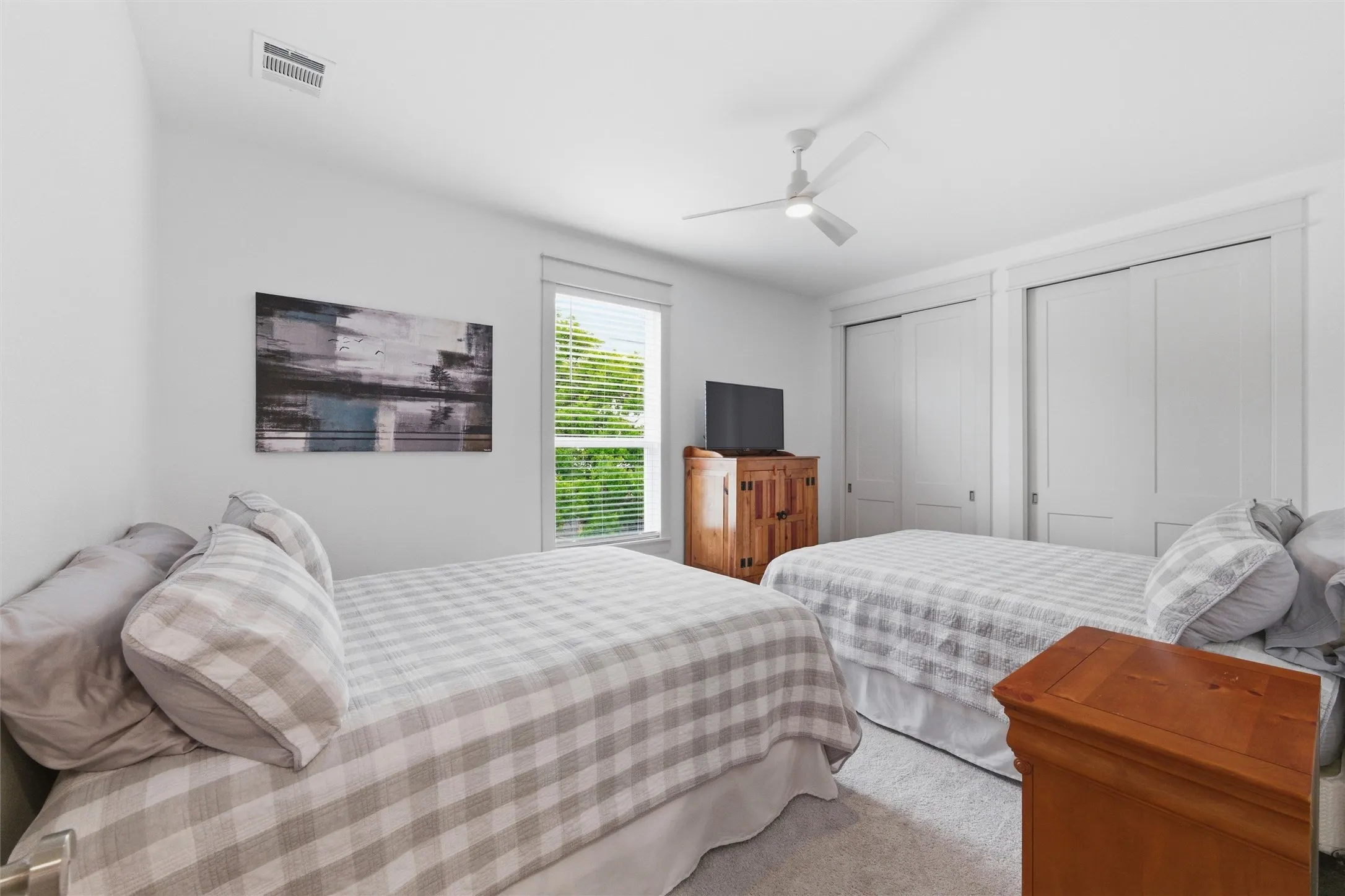 Secondary bedroom features recessed lighting, ceiling fan, large window for natural light, soft carpeting, and neutral finishes throughout the space.