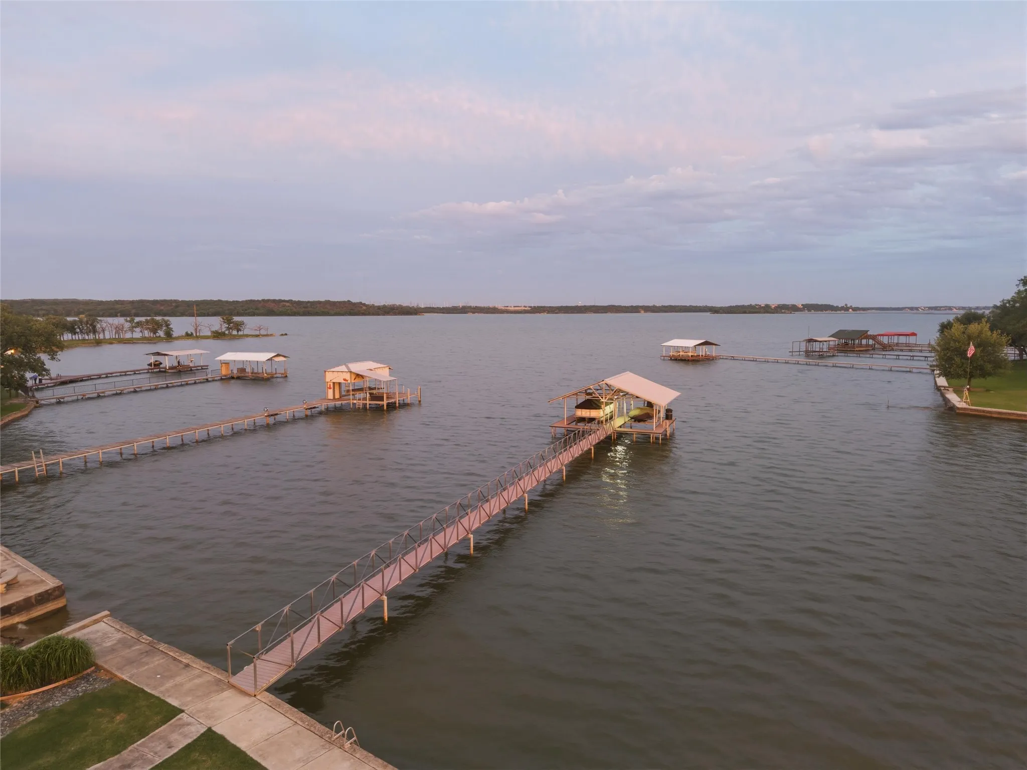 Lake view showcases expansive waterfront views with surrounding shoreline visibility and direct dock access extending into the lake. Open water views and landscaped shoreline areas create a wide exterior waterfront setting.