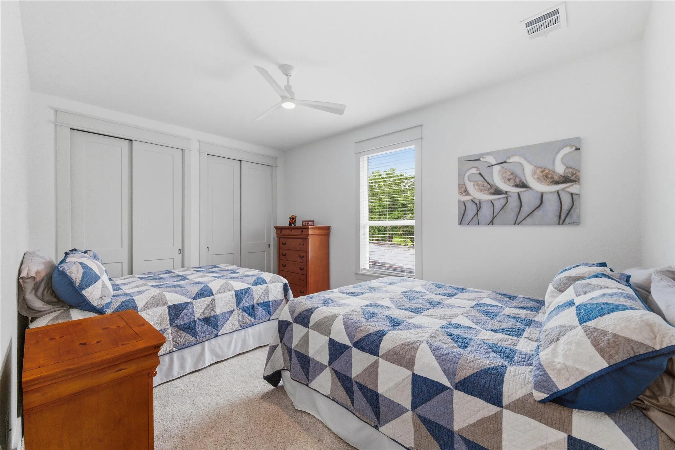 Secondary bedroom features recessed lighting, ceiling fan, large window for natural light, soft carpeting, and spacious layout throughout the room.
