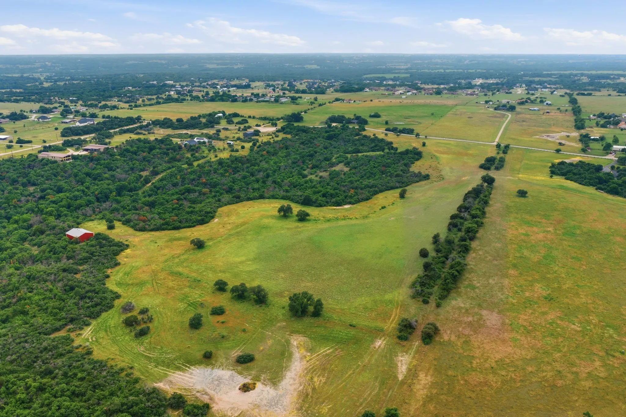 This aerial view highlights the property’s peaceful seclusion, showcasing gently sloping land, abundant trees, and breathtaking countryside scenery.