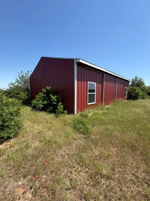 The striking red barn adds classic country charm to the property, standing out beautifully against the rolling landscape and mature trees.