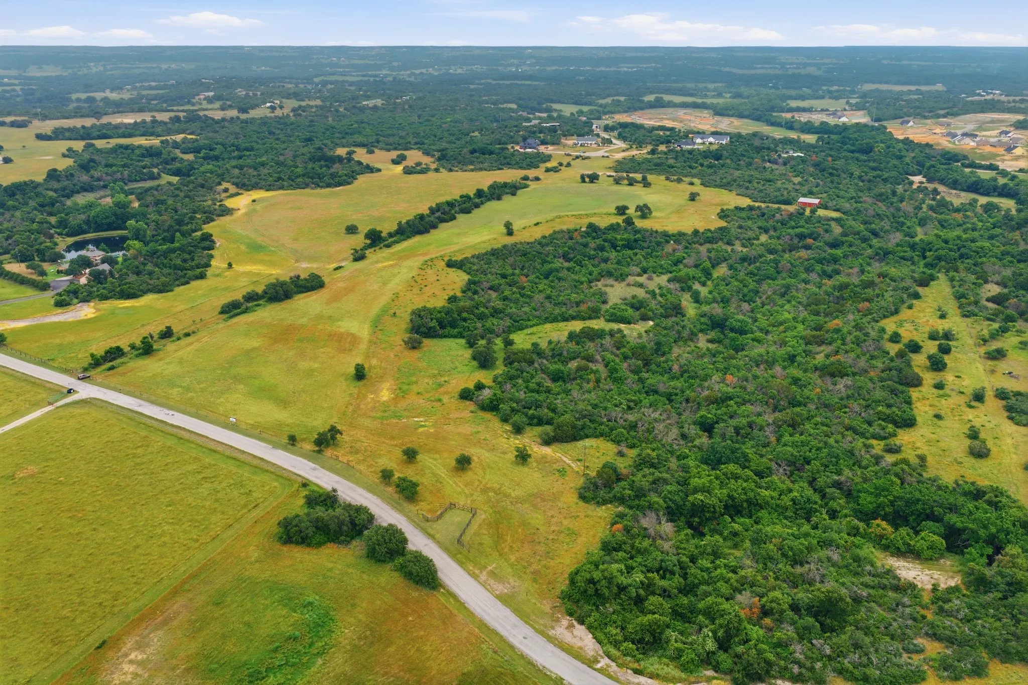 Sweeping aerial views capture the peaceful charm of the land, highlighting the natural contours, expansive acreage, and serene country atmosphere.