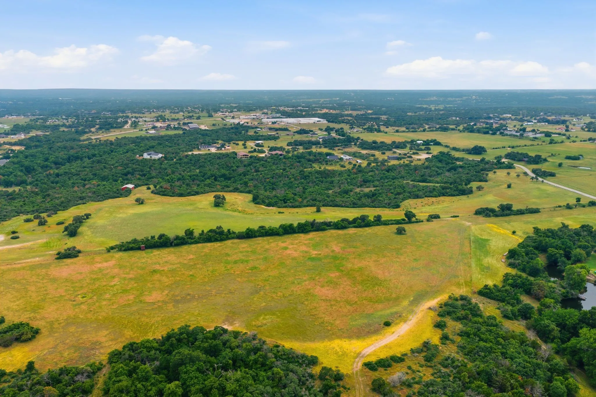 A panoramic aerial view offers a true sense of the property’s scale and beauty, featuring rolling countryside, scattered hardwoods, and endless opportunities for the future.