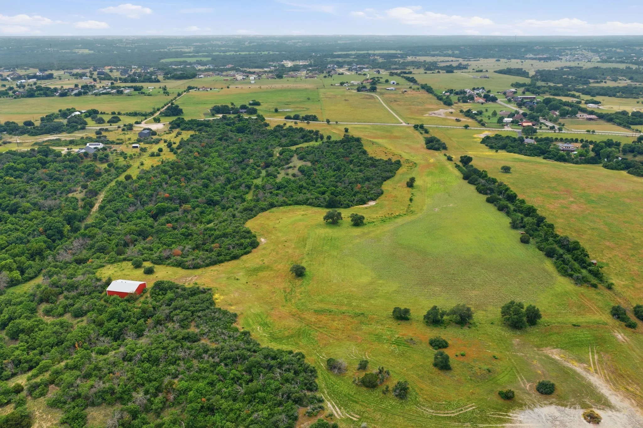 A stunning aerial angle reveals the expansive size and versatility of this 54-acre property, where open spaces and wooded areas blend seamlessly together.