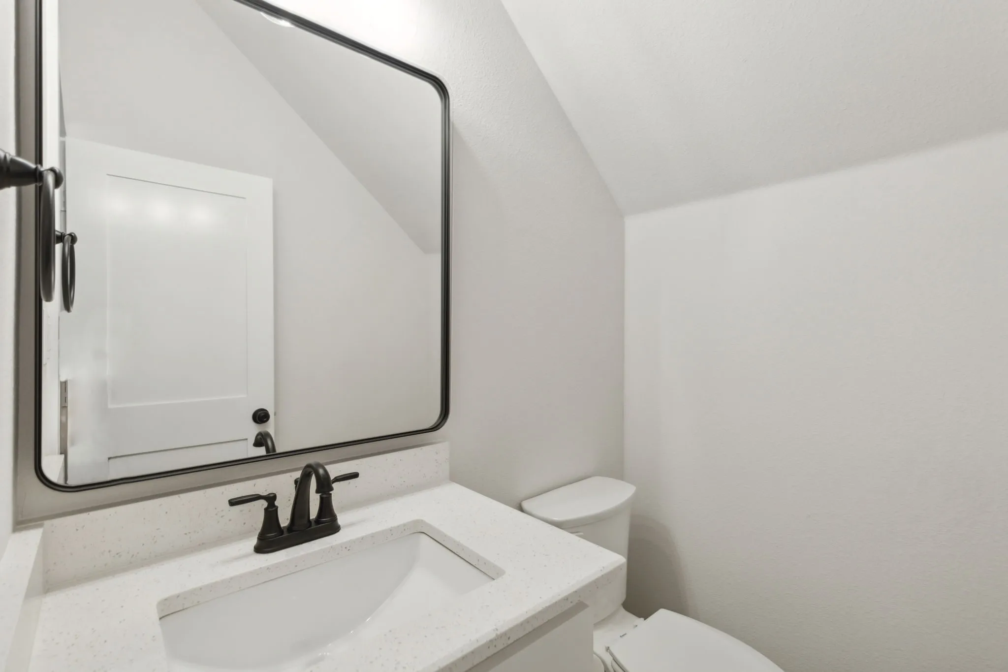 Bathroom featuring a vanity with an integrated sink, a speckled countertop, and a matte black faucet