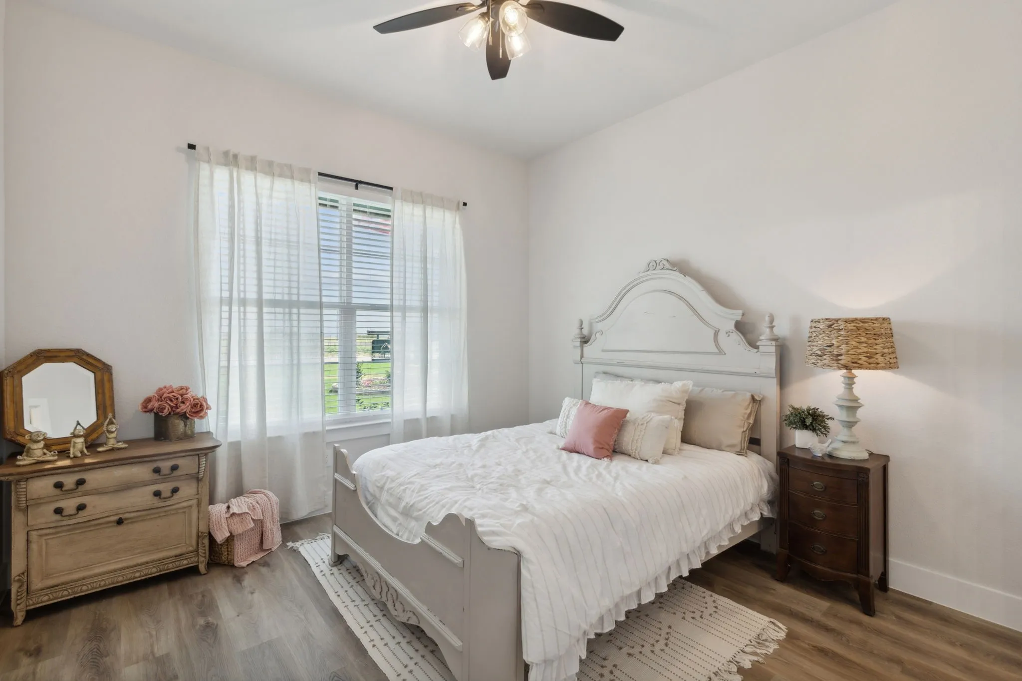 Room featuring wood-finish flooring, a ceiling fan with integrated lighting, and a large window with horizontal blinds