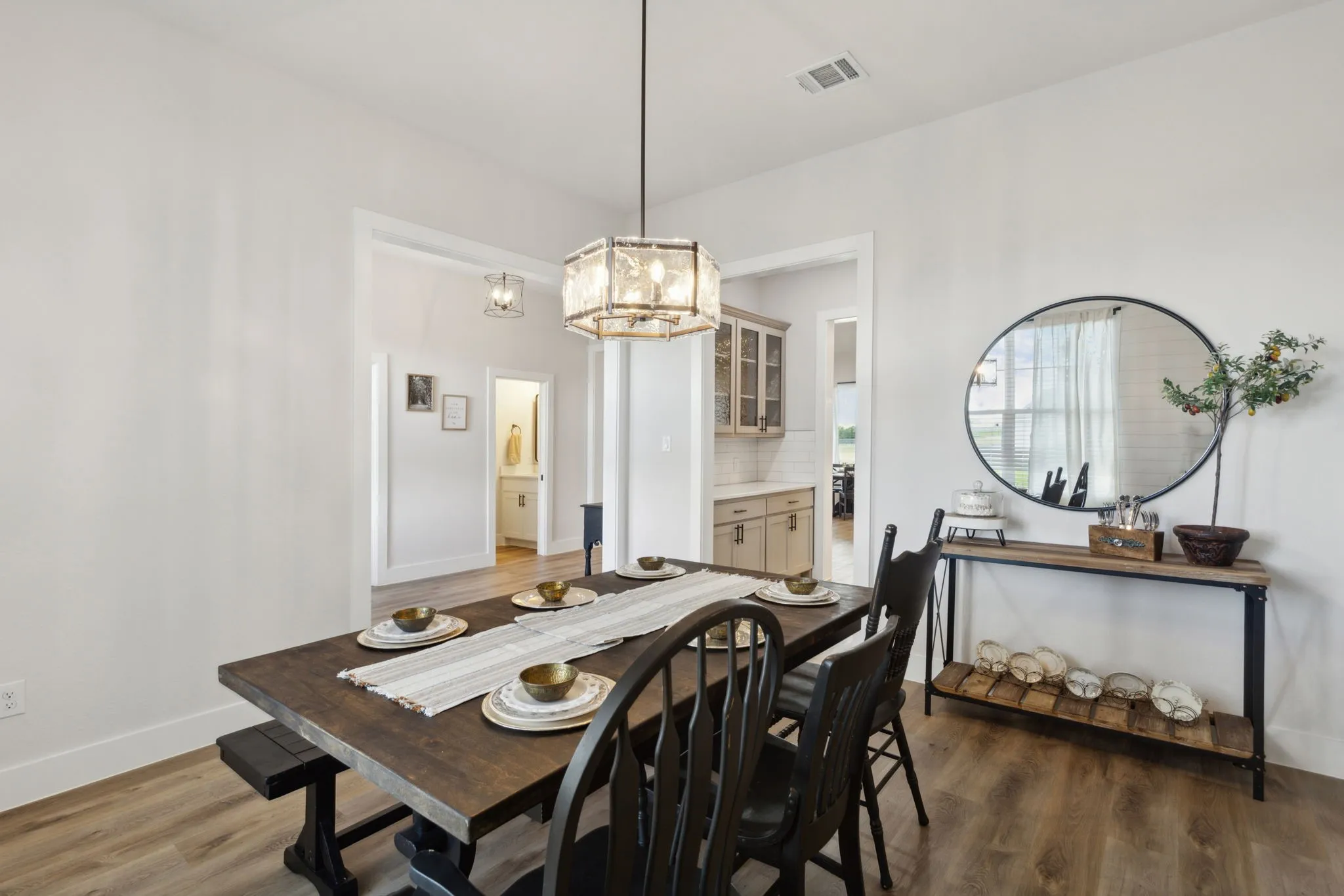 Spacious dining area featuring wood-finish flooring, a contemporary chandelier, and bright white walls