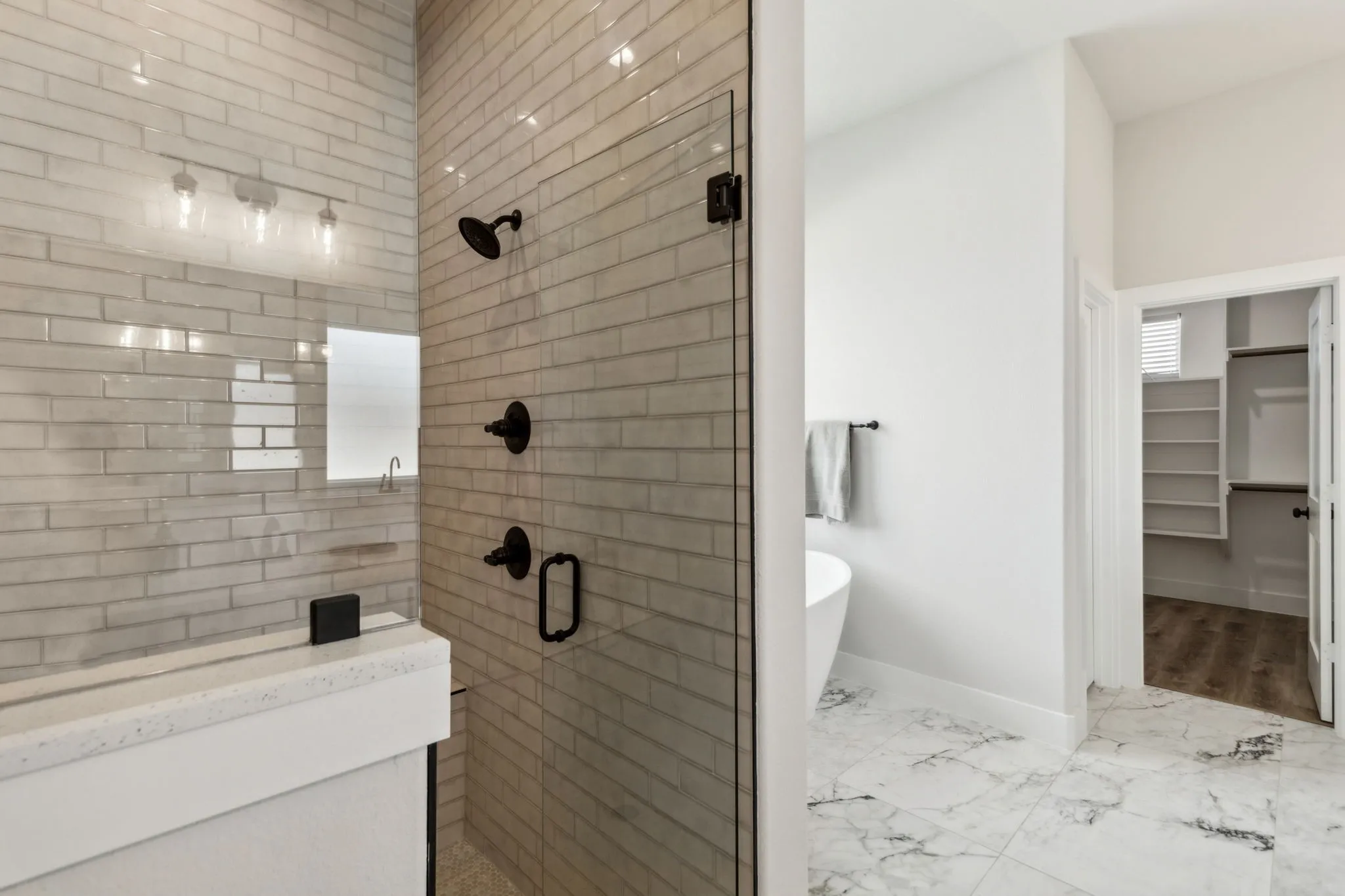 Glass-enclosed shower with subway tile surround and matte black fixtures