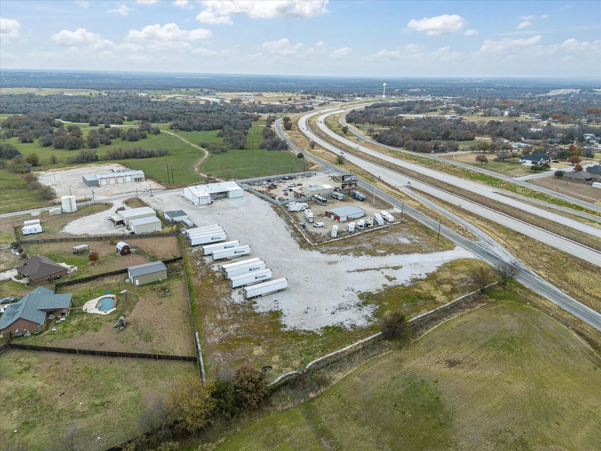 Expansive commercial property featuring multiple structures, gravel surfacing, and direct highway frontage