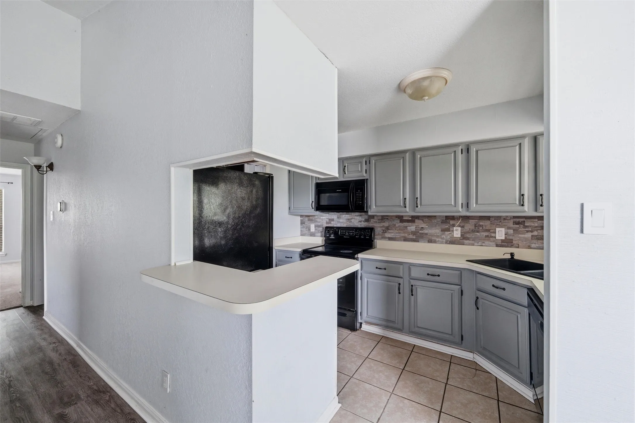 Kitchen featuring gray cabinetry, light countertops, and a tiled backsplash