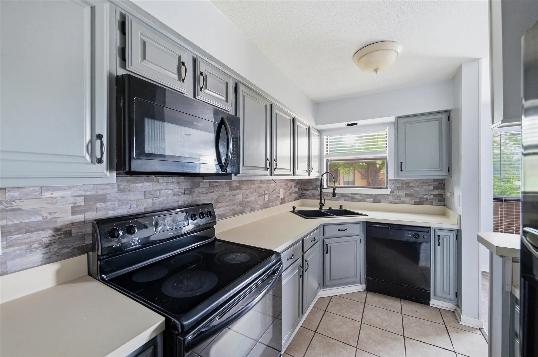 Kitchen featuring gray cabinetry, light countertops, and a tiled backsplash