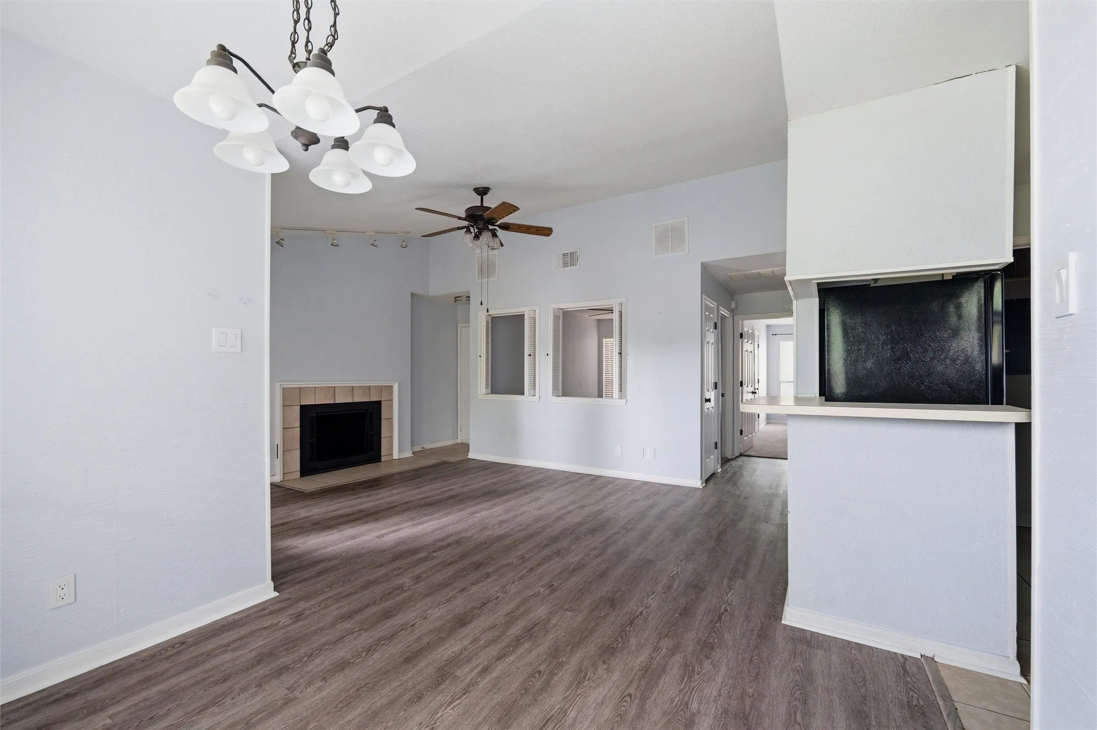 Spacious interior featuring wood-finish flooring, a fireplace with a tile surround, and an overhead ceiling fan
