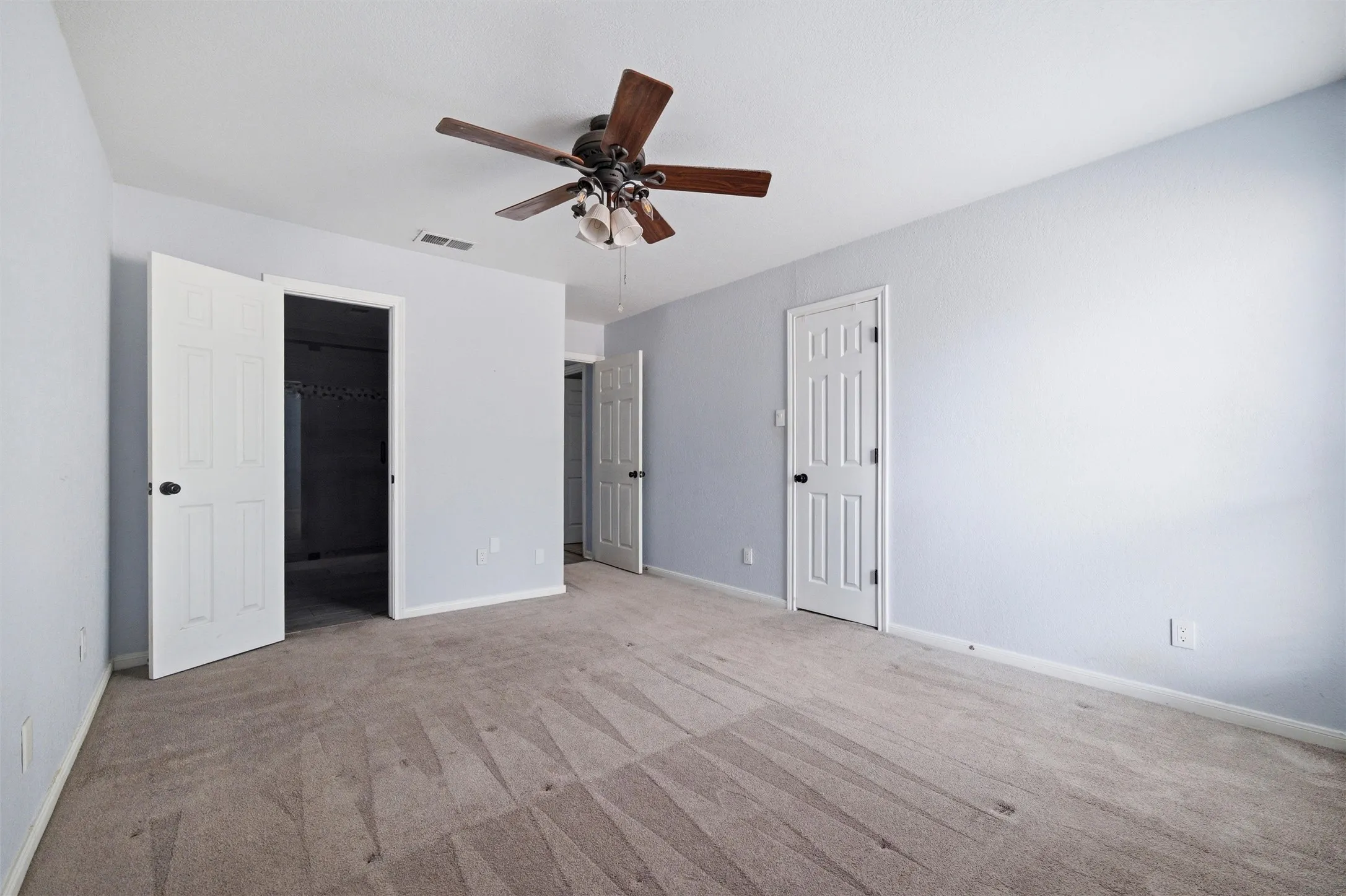 Spacious room featuring light gray walls and neutral carpet flooring