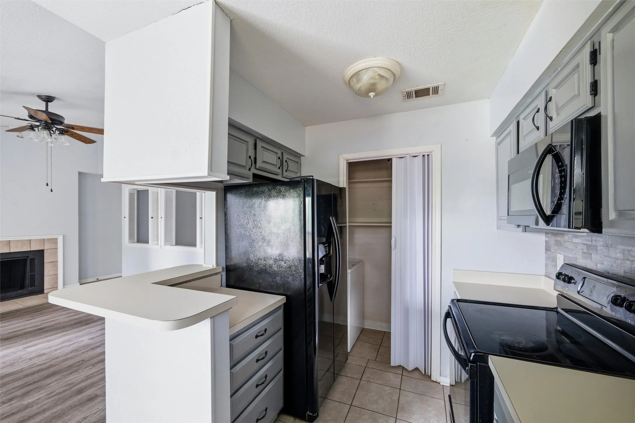 Kitchen featuring gray cabinetry with black hardware, black refrigerator, and built-in microwave