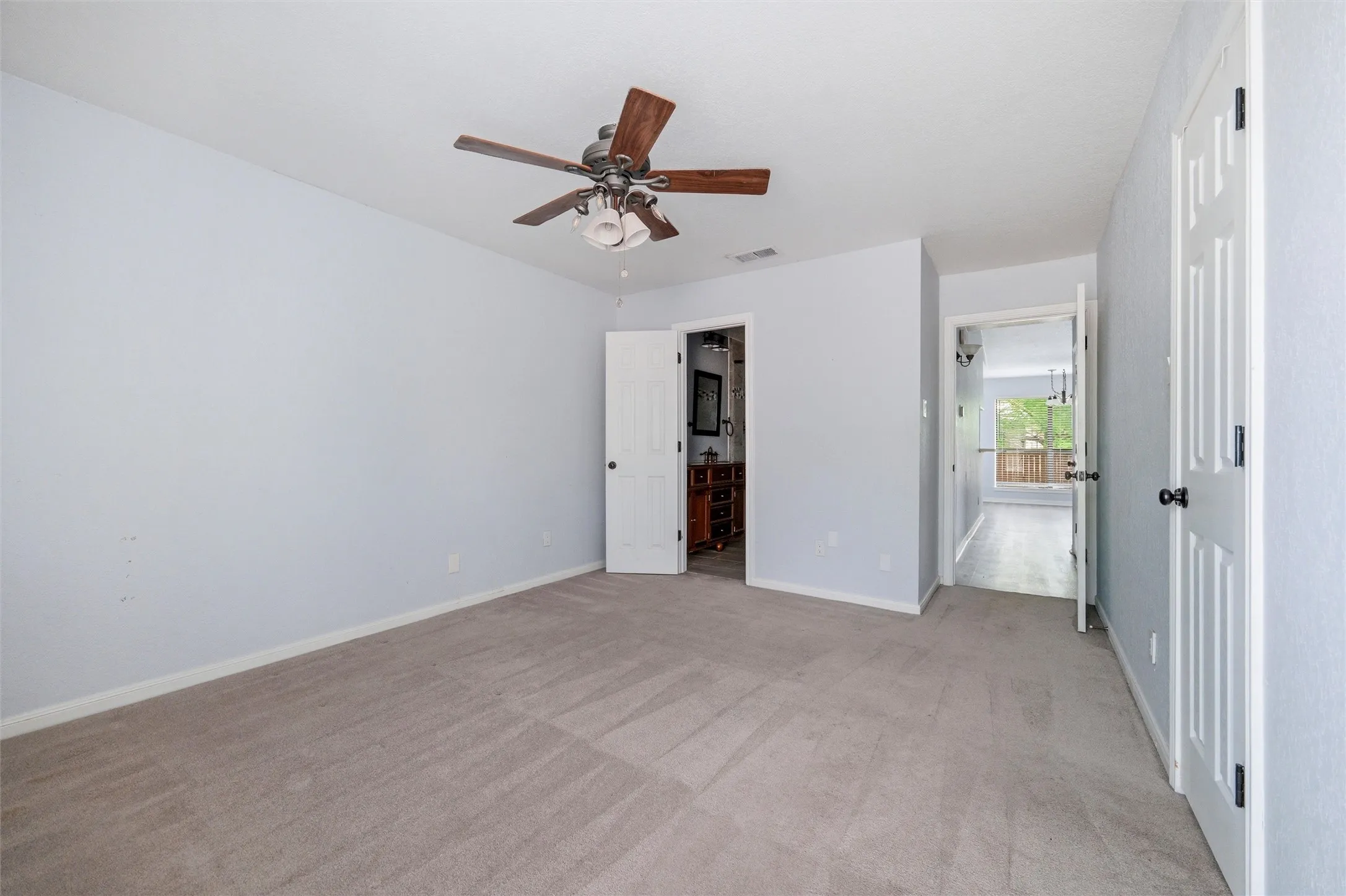 Spacious room featuring neutral carpeting, light-toned walls, and white trim