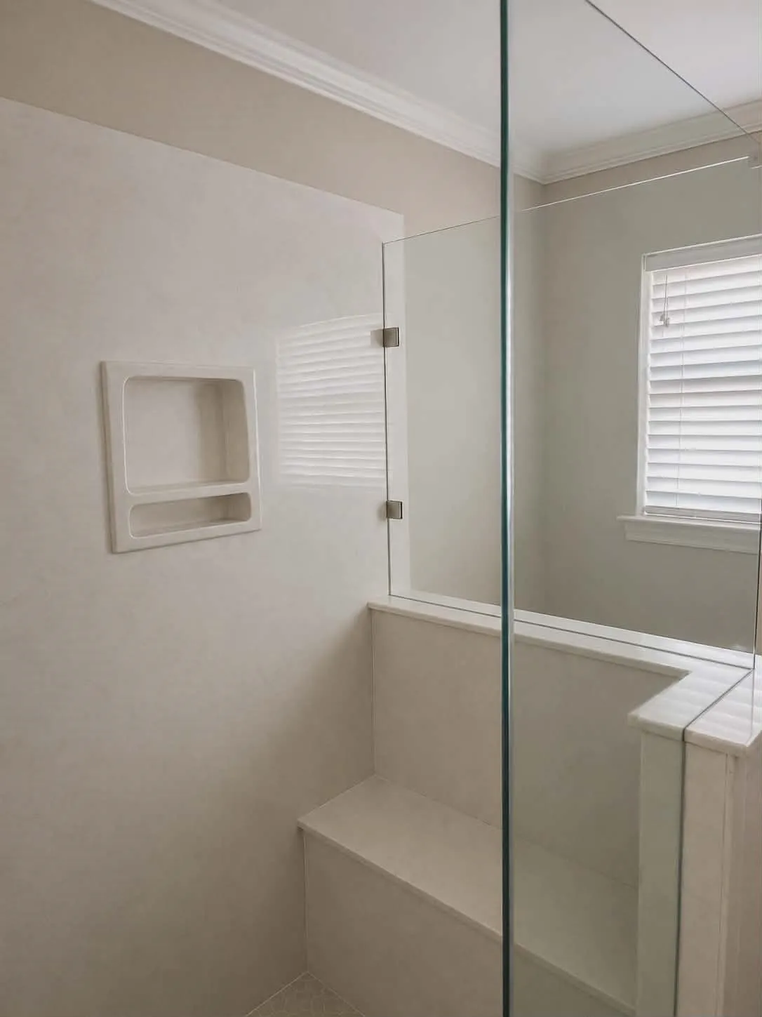 Shower enclosure featuring a built-in bench, recessed shelf, and clear glass panels with polished chrome hardware-This photo was taken before family moved in