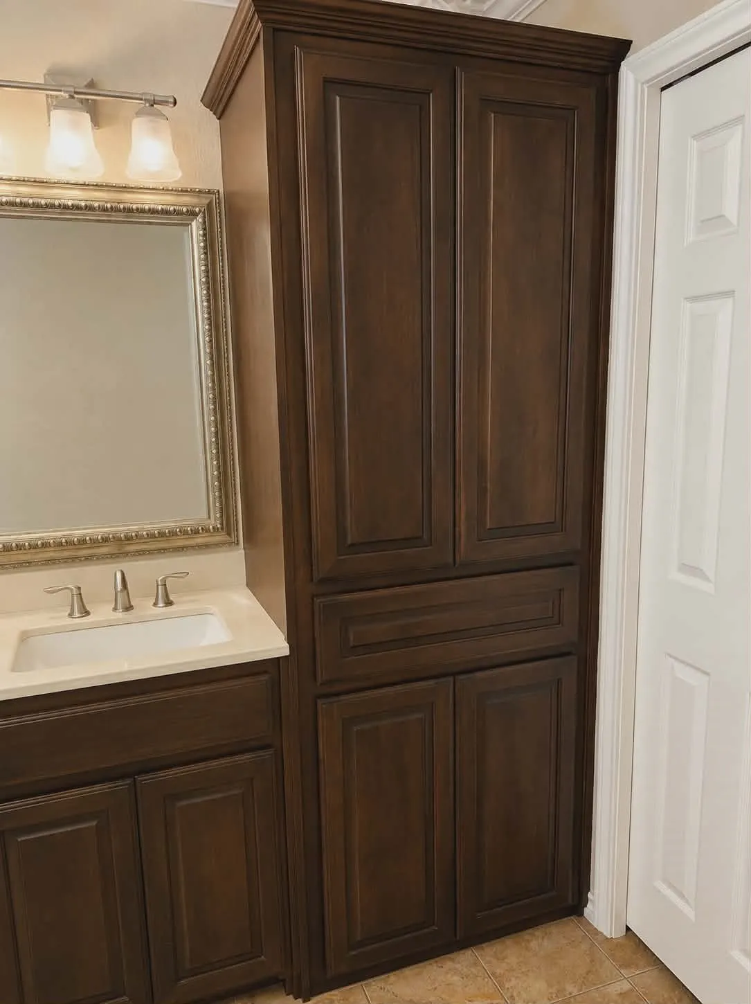 Bathroom cabinet featuring dark wood-finish cabinetry, a light-toned countertop, and an undermount sink-This photo was taken before family moved in