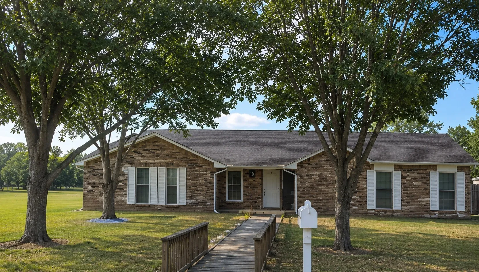 Brick exterior with white shutters and a dark shingle roof