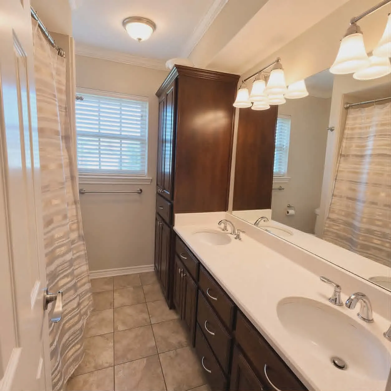 Full second bathroom featuring a double vanity with integrated sinks, dark wood-finish cabinetry, and a full-width mirror-This photo was taken before family moved in