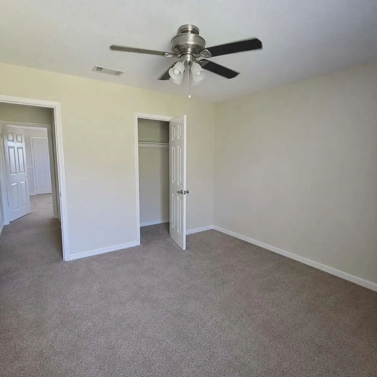 Bedroom 2- Interior room featuring neutral-toned walls, plush carpet flooring, and a ceiling fan with integrated lighting-This photo was taken before family moved in