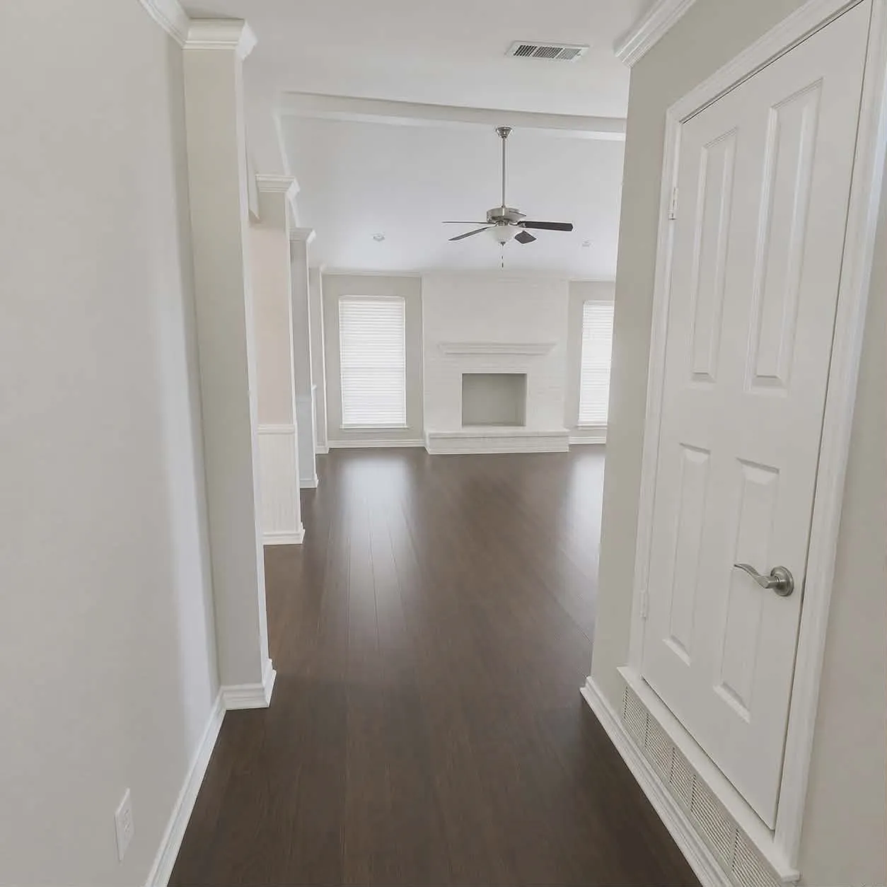 Spacious interior with dark wood-finish flooring, white baseboards, and crown molding- This photo was taken before family moved in
