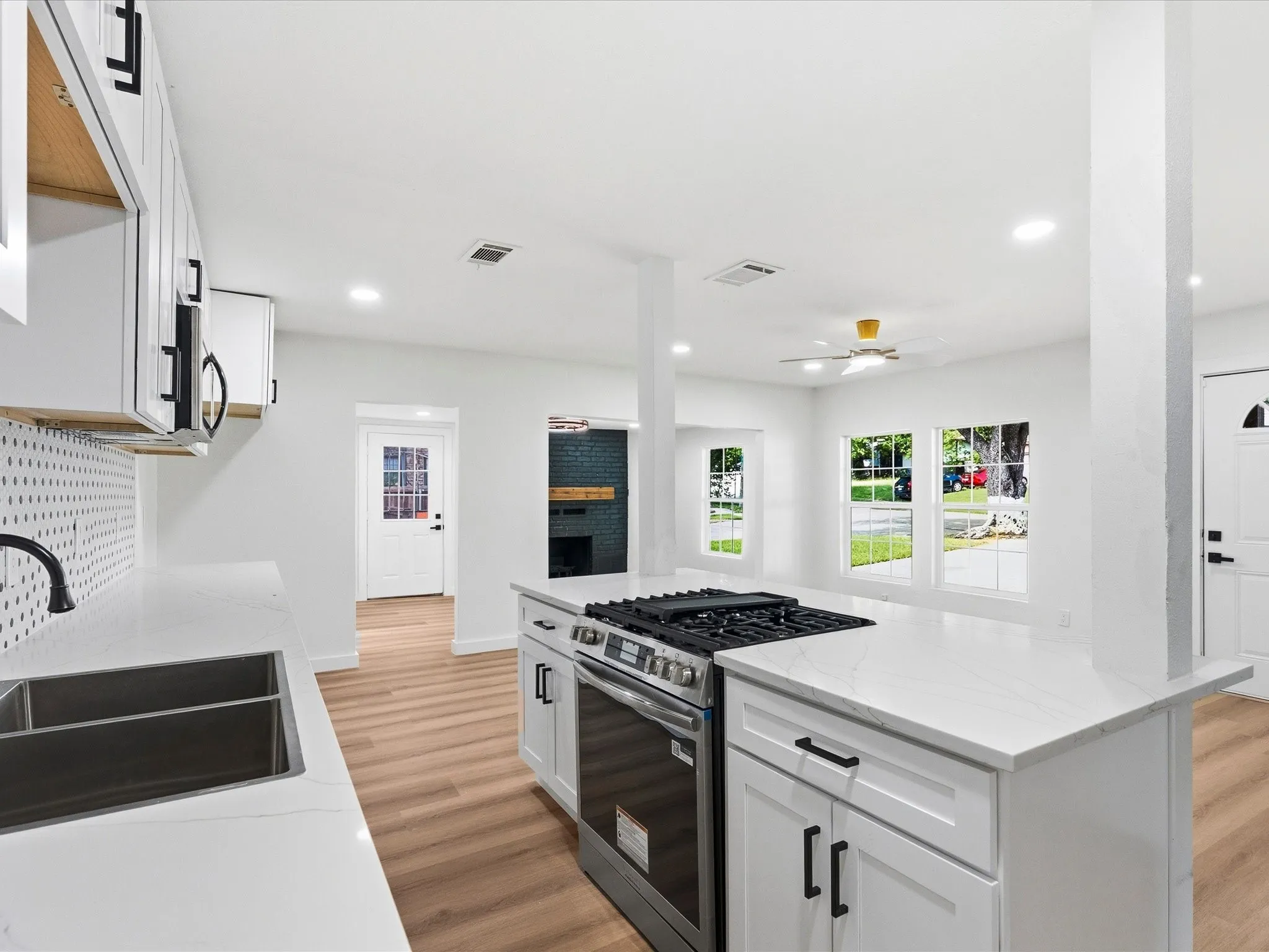 Modern kitchen featuring white shaker cabinetry, quartz countertops, a double basin sink, stainless steel range, and wood-finish flooring
