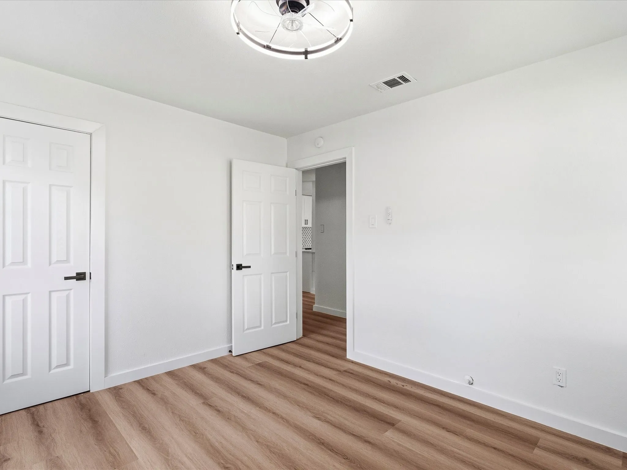 Room featuring wood-finish flooring, white painted walls, and a contemporary ceiling fixture