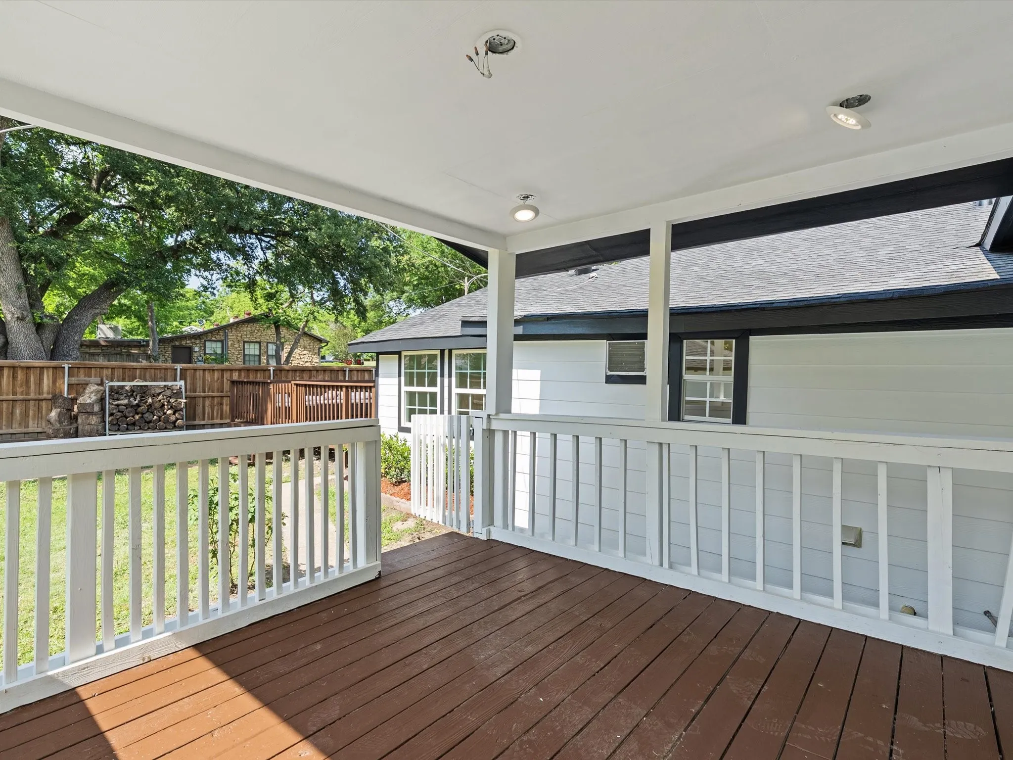 Covered outdoor patio featuring wood-finish decking and white baluster railing