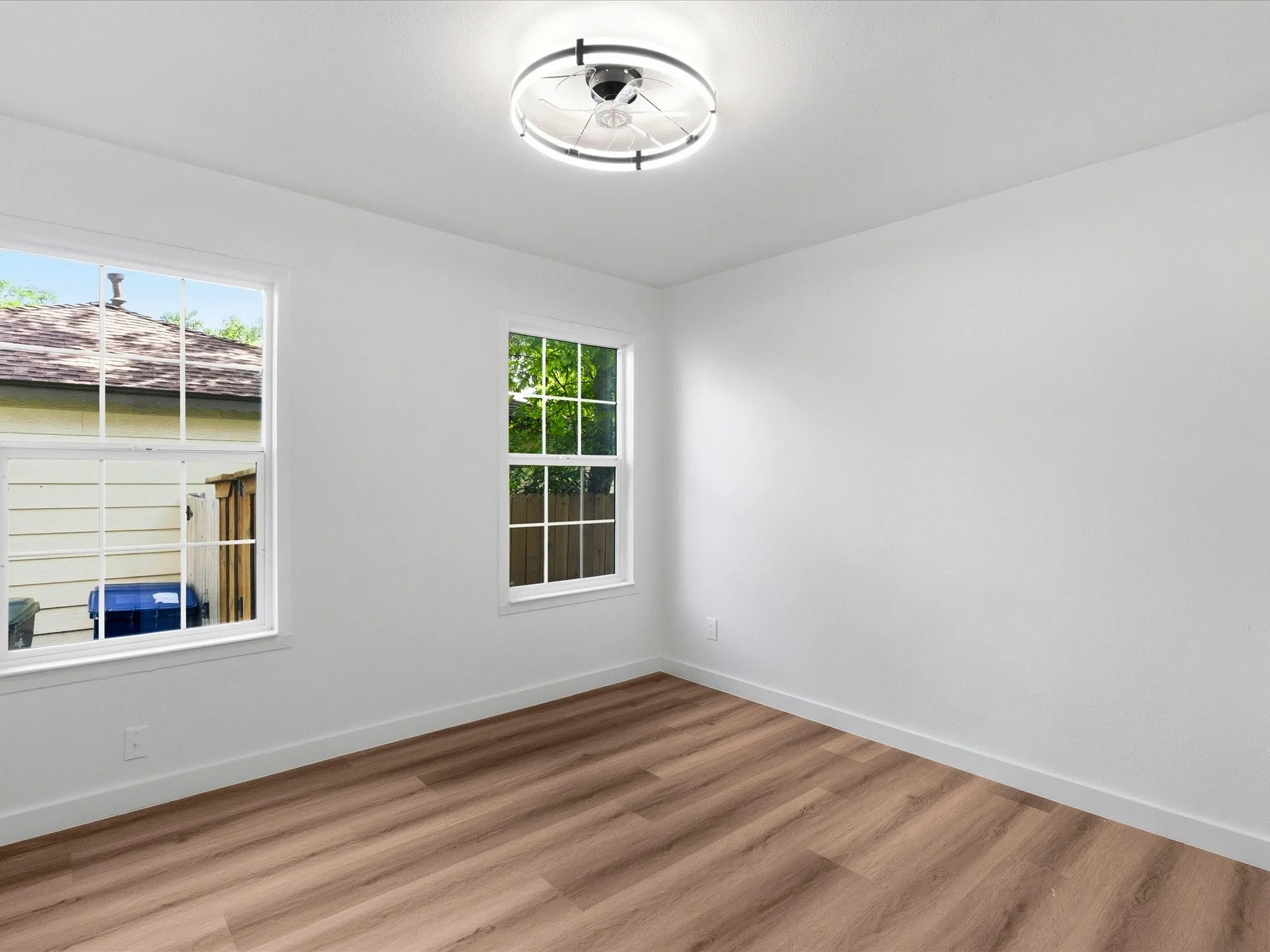 Bright room with wood-finish flooring, white walls, and a modern ceiling light fixture