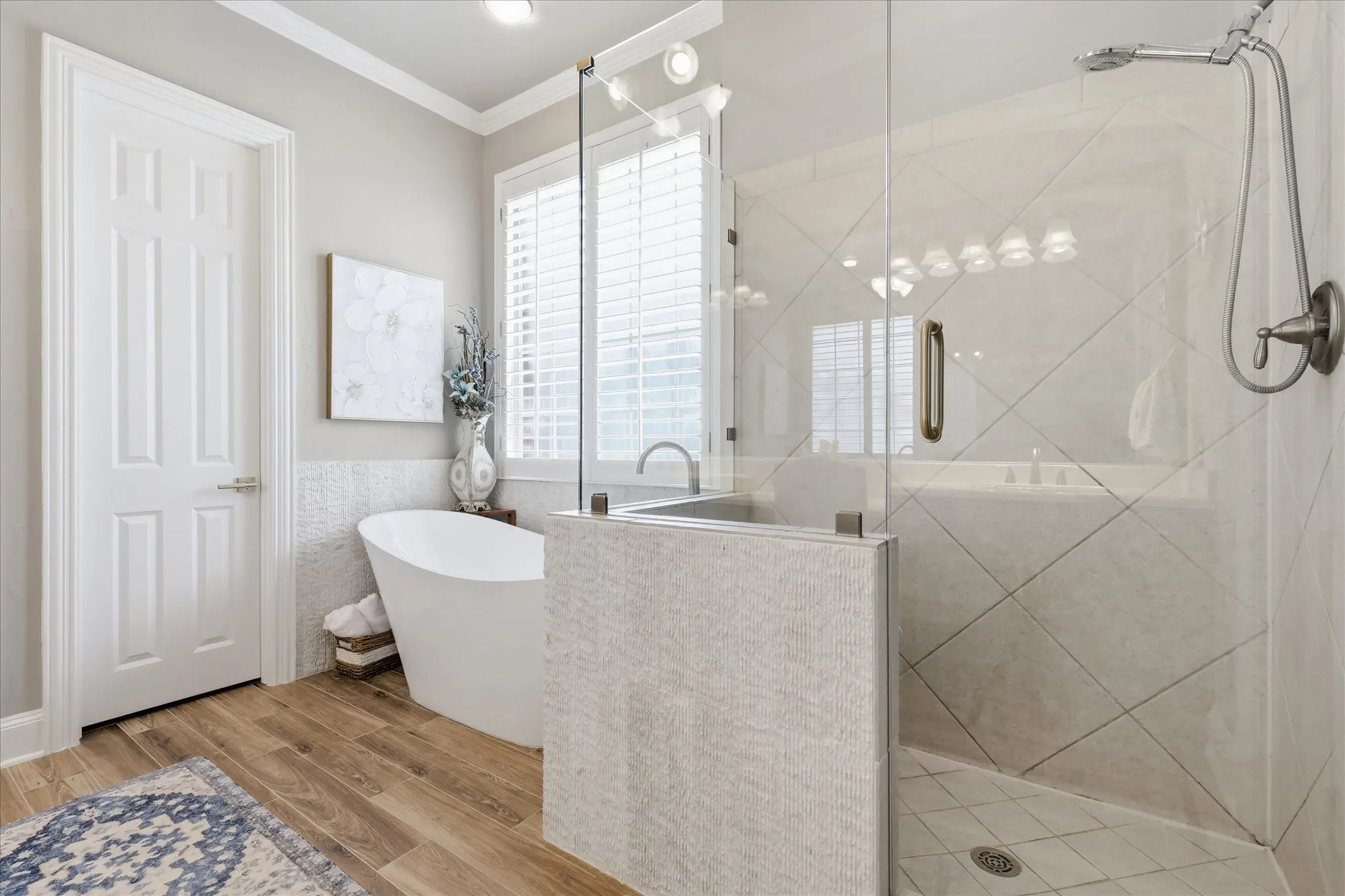 Freestanding soaking tub alongside a glass-enclosed shower with a diagonal tile pattern