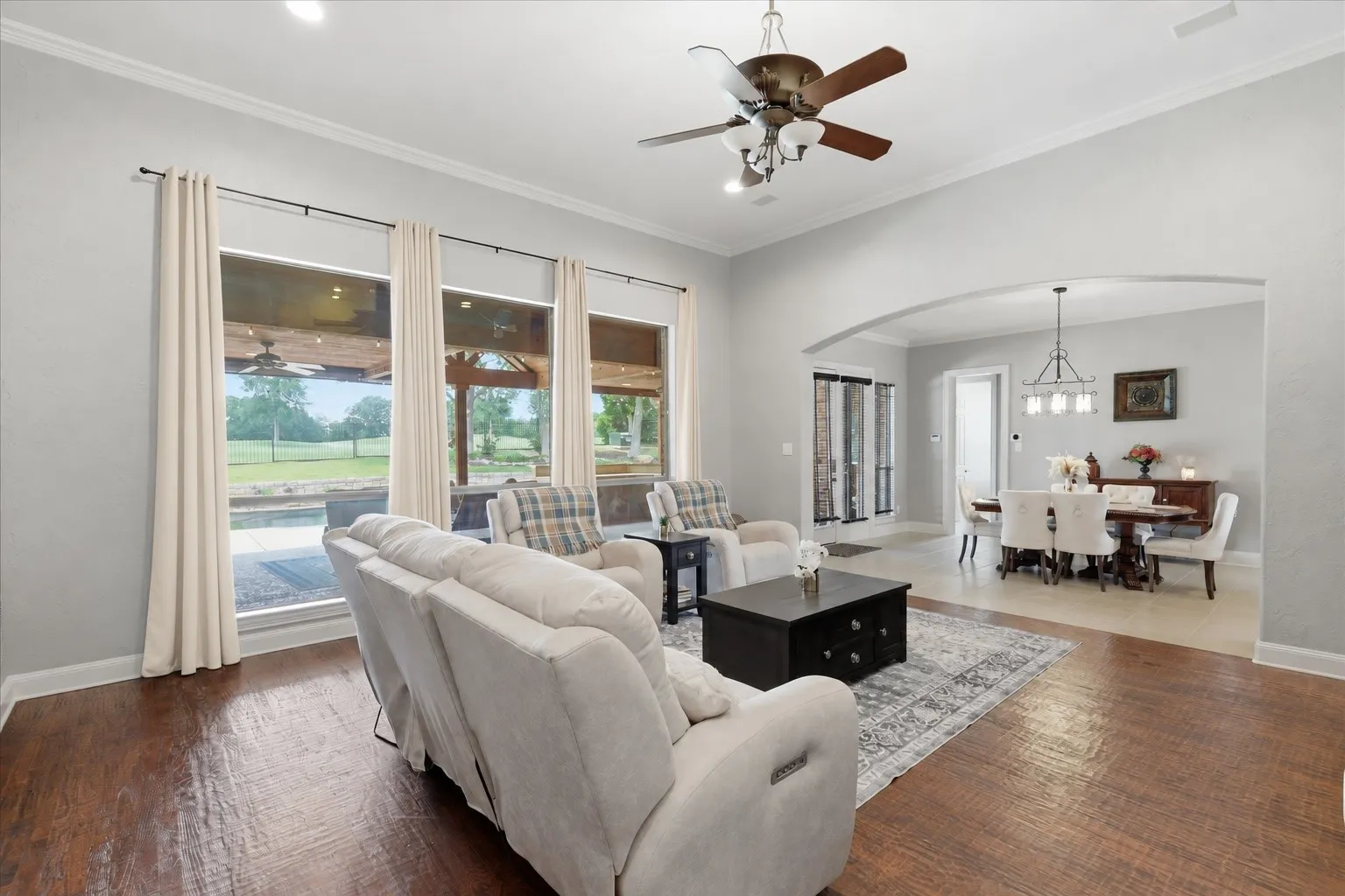 Vaulted ceiling living area with wood-finish flooring, recessed lighting, and multiple windows