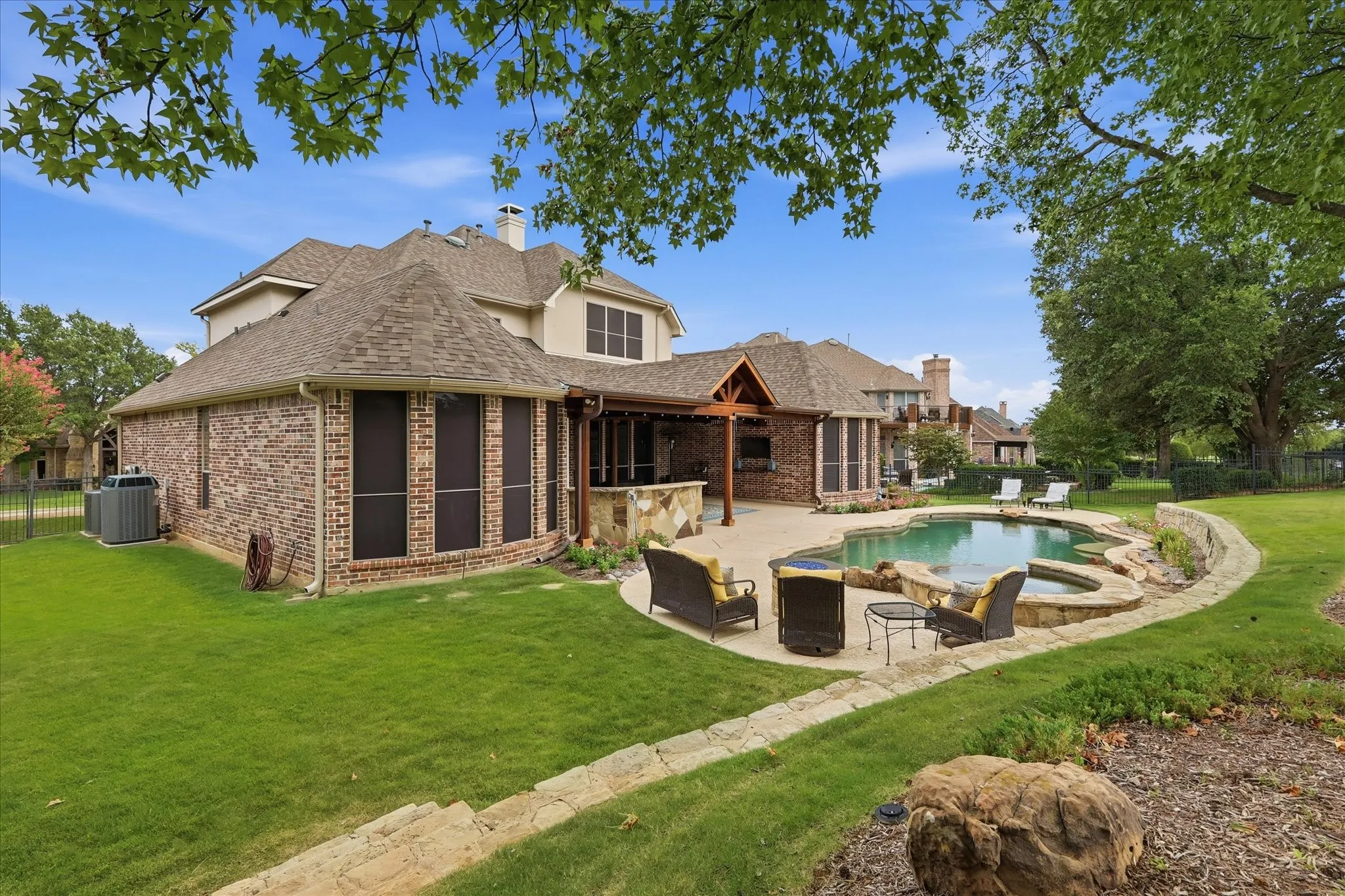 Rear exterior featuring a free-form pool, integrated spa, and expansive paved patio