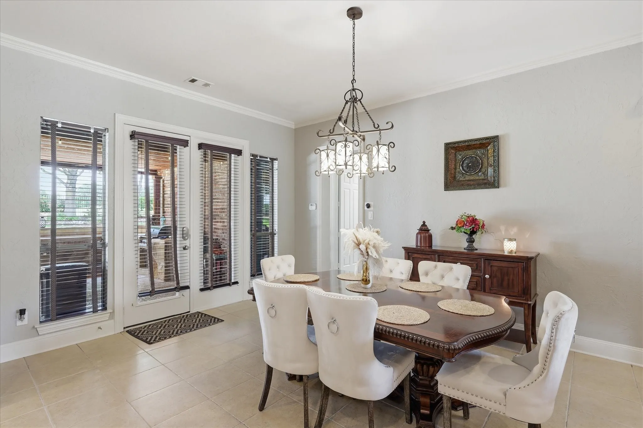 Spacious dining area featuring neutral wall tones, crown molding, and large-format tile flooring