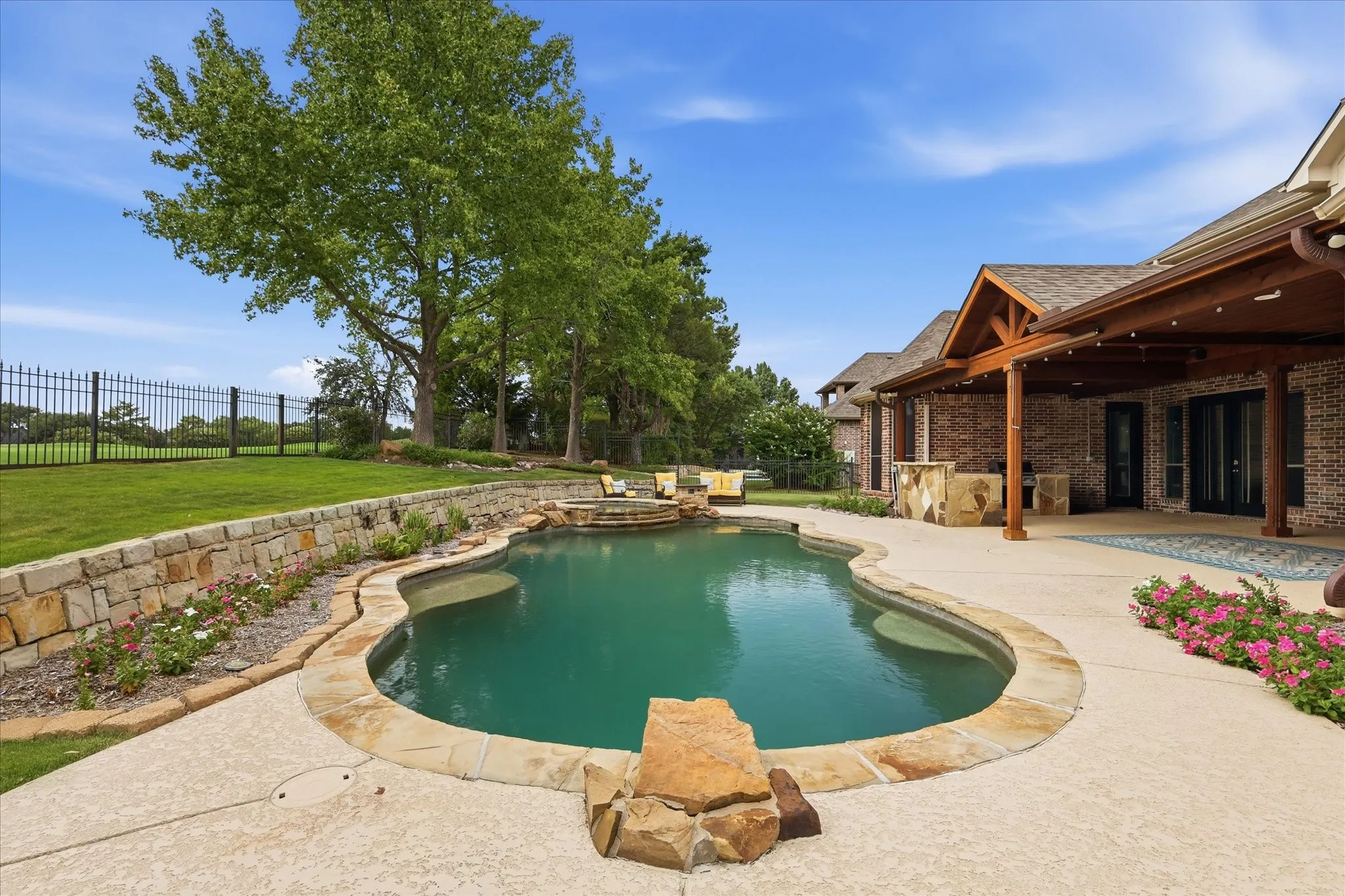 Freeform swimming pool with integrated spa and stone coping