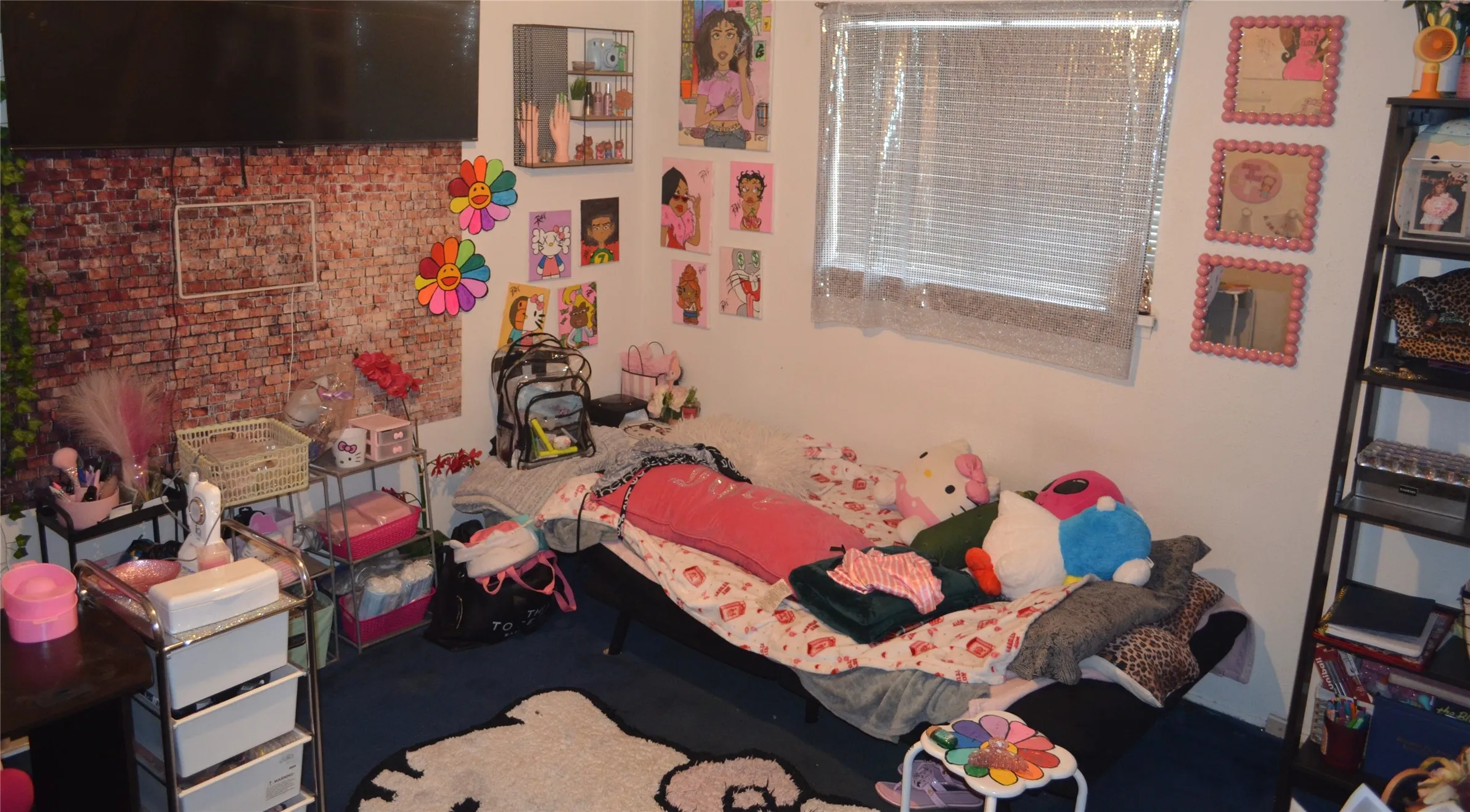 Room featuring a brick-patterned accent wall, wall-mounted television, window with horizontal blinds, built-in shelving, and dark-toned flooring