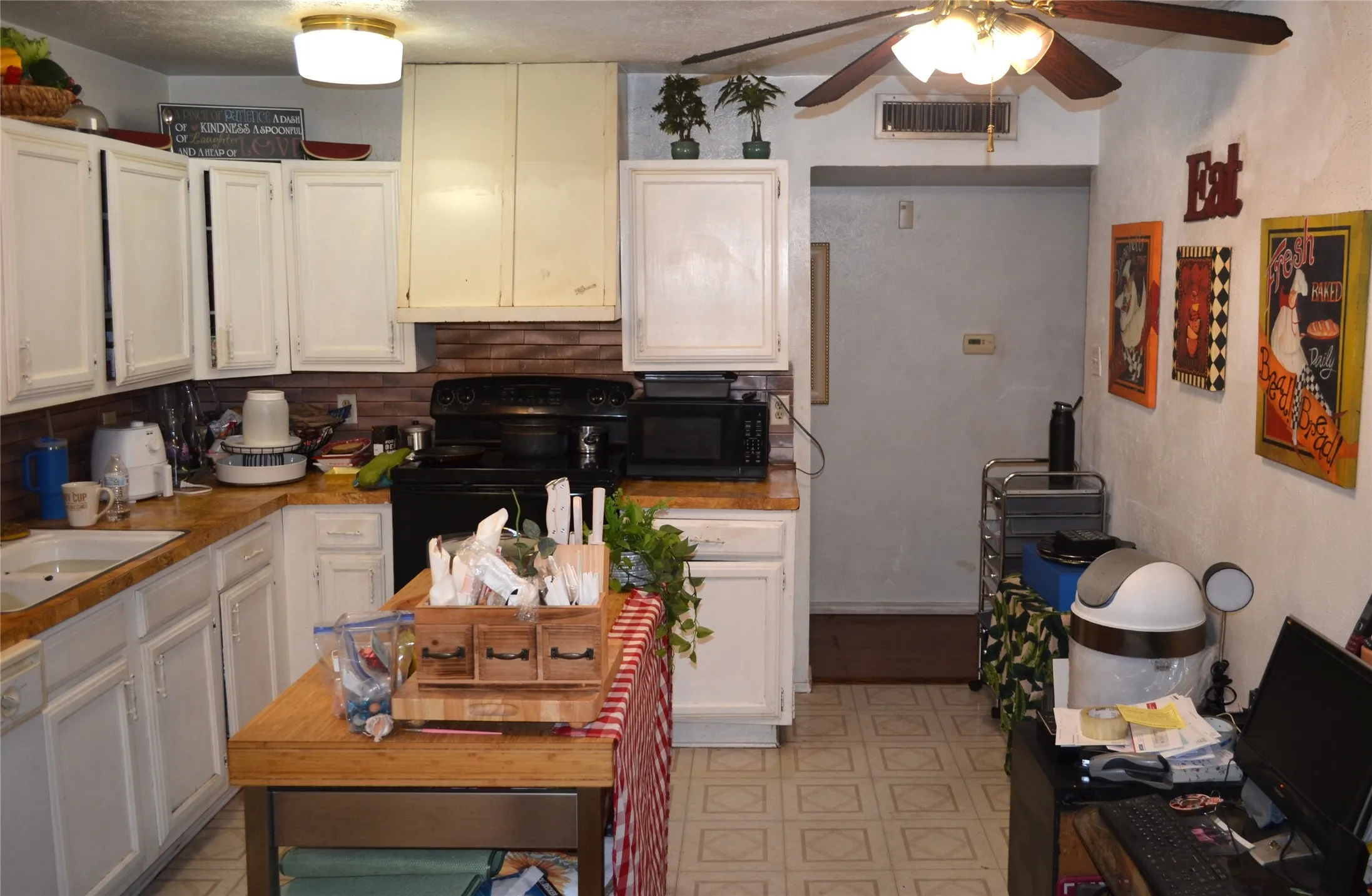 Kitchen featuring white cabinetry, a black range, wood-finish countertops, and a ceiling fan
